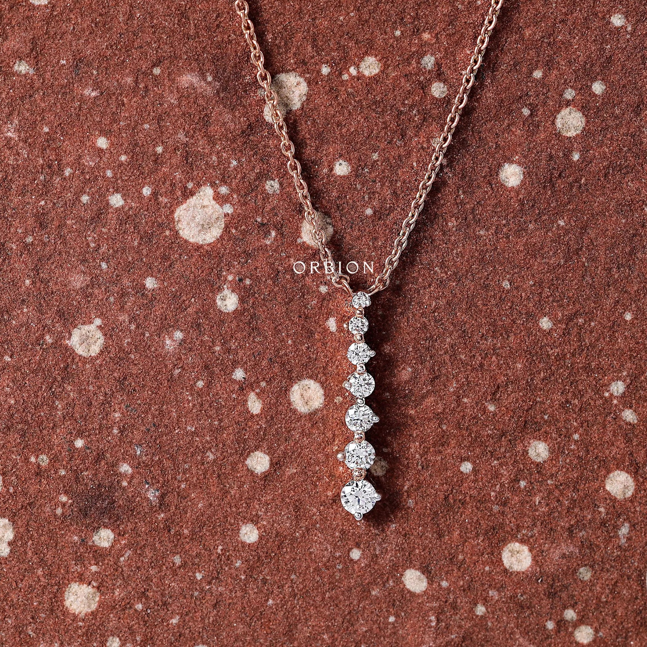 Close-up shot of a vertical drop pendant with graduated diamonds set in rose gold.