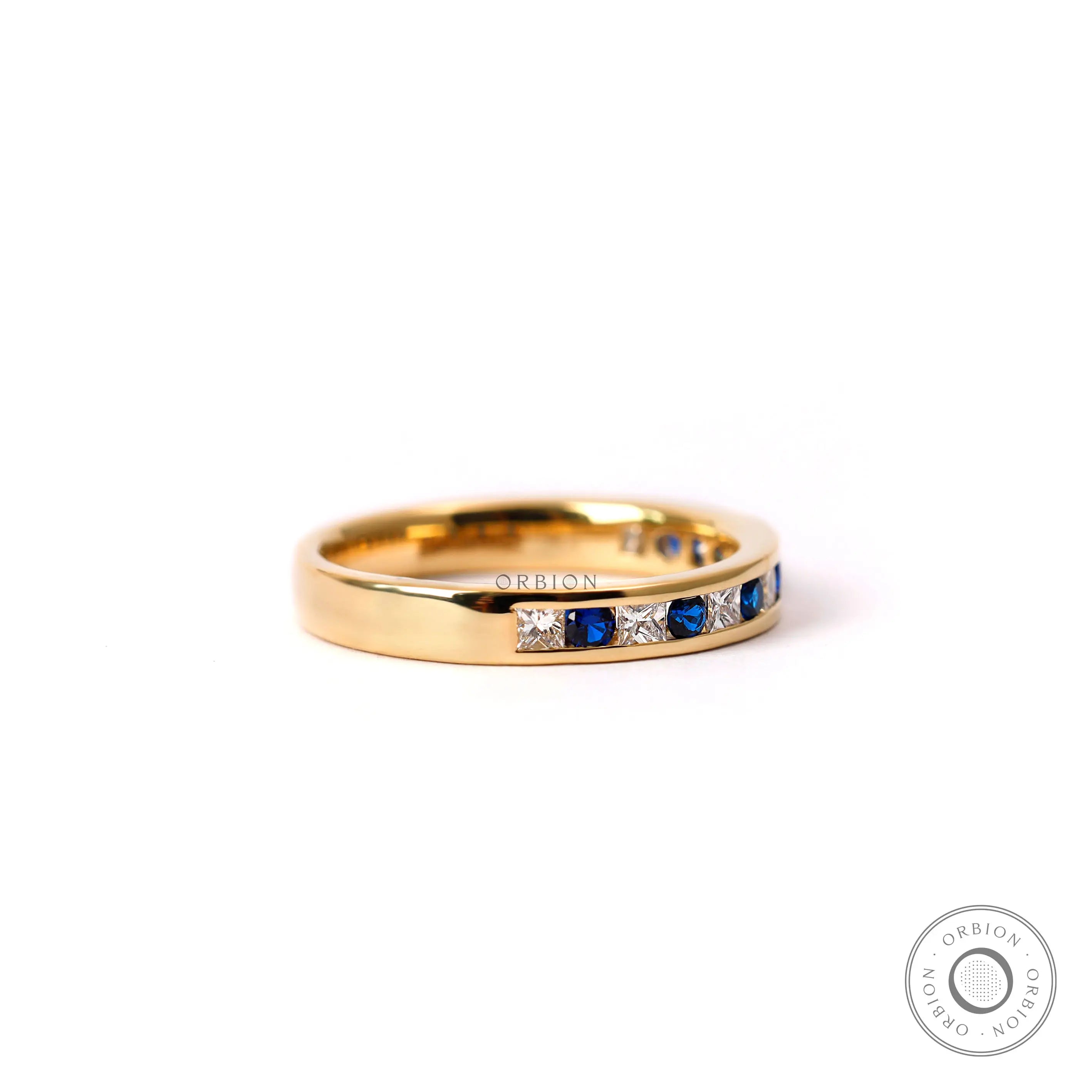 Diamond and blue sapphire half eternity band in yellow gold studio image