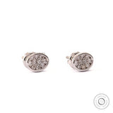 Close up of dainty white gold stud earrings with lab grown diamonds in oval shape.