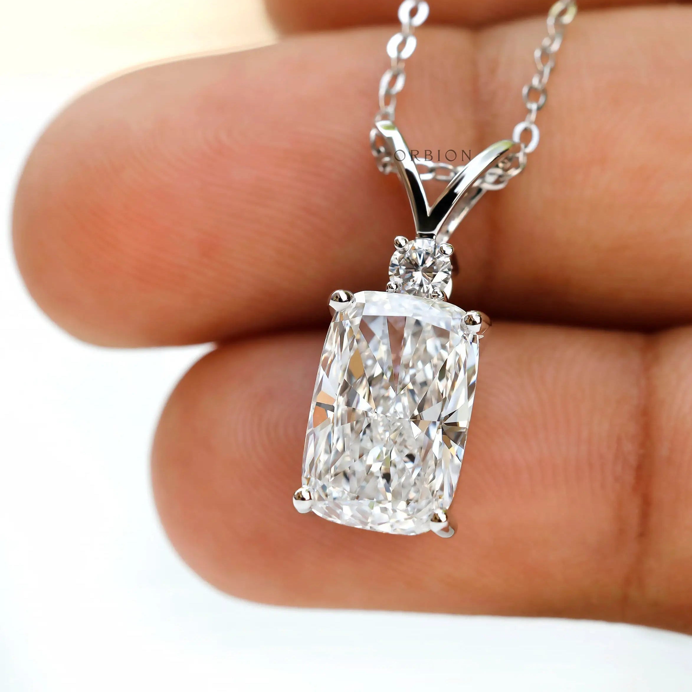 Close up of elongated cushion diamond pendant with accent stone.