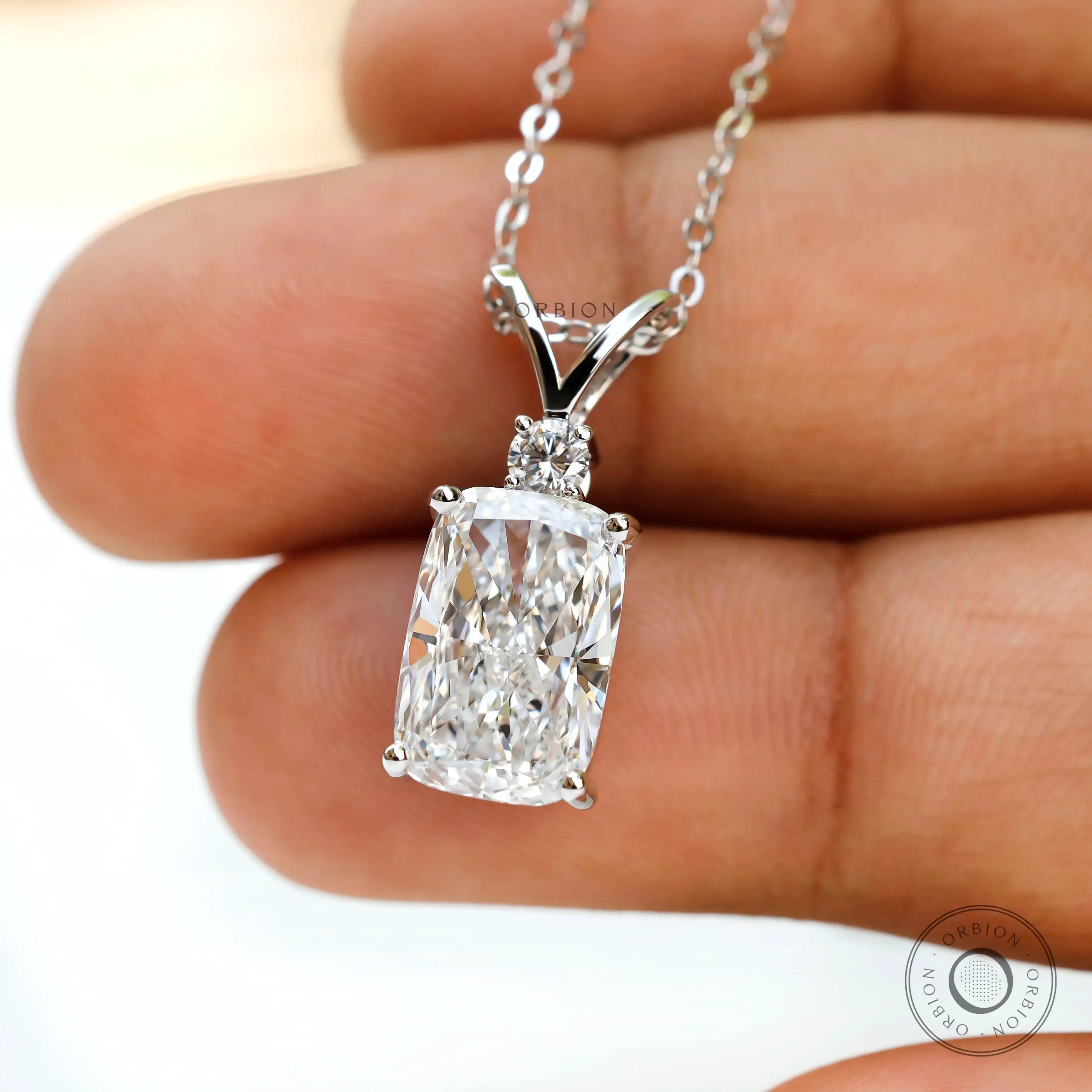 Close up of elongated cushion diamond pendant with accent stone.