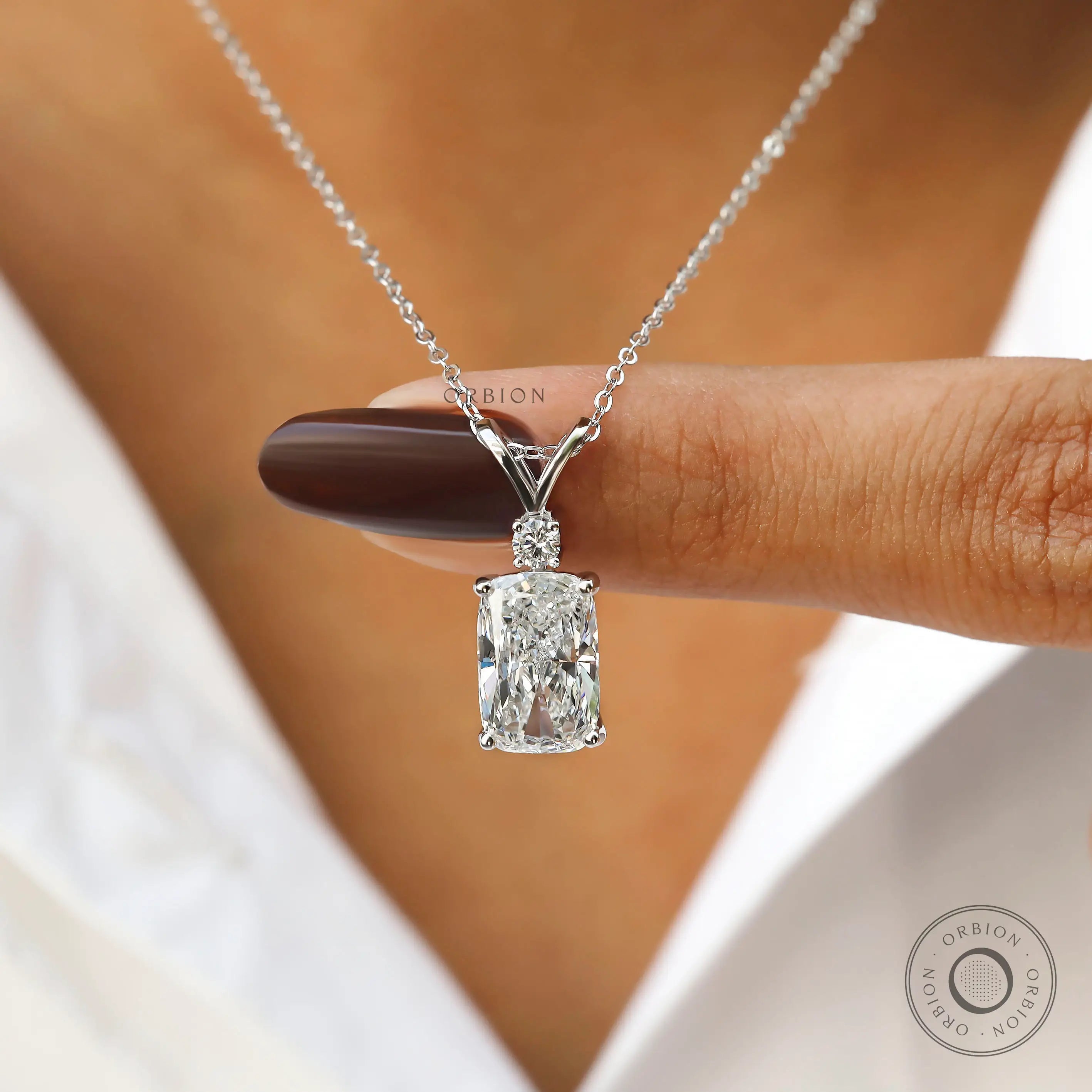 Finger held view of elongated cushion lab diamond pendant.