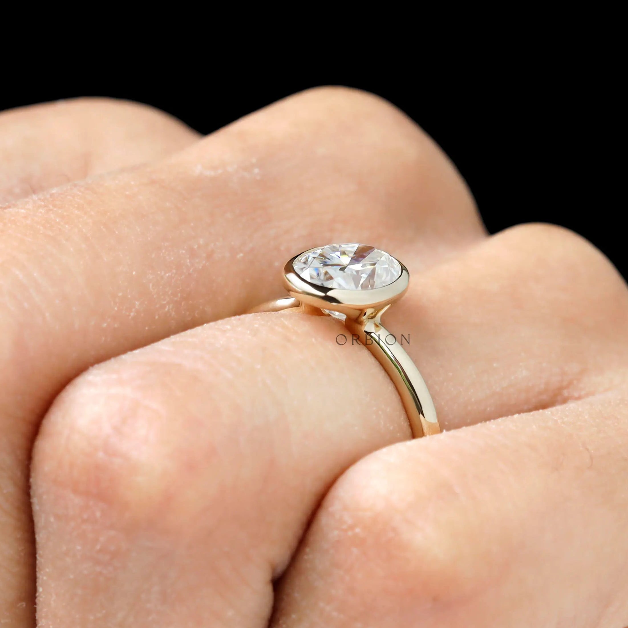 Bezel set oval moissanite ring on finger view