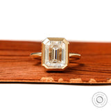 emerald cut moissanite bezel engagement ring with pave halo detail