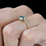 Minimal yellow gold engagement ring with blue green moissanite center stone