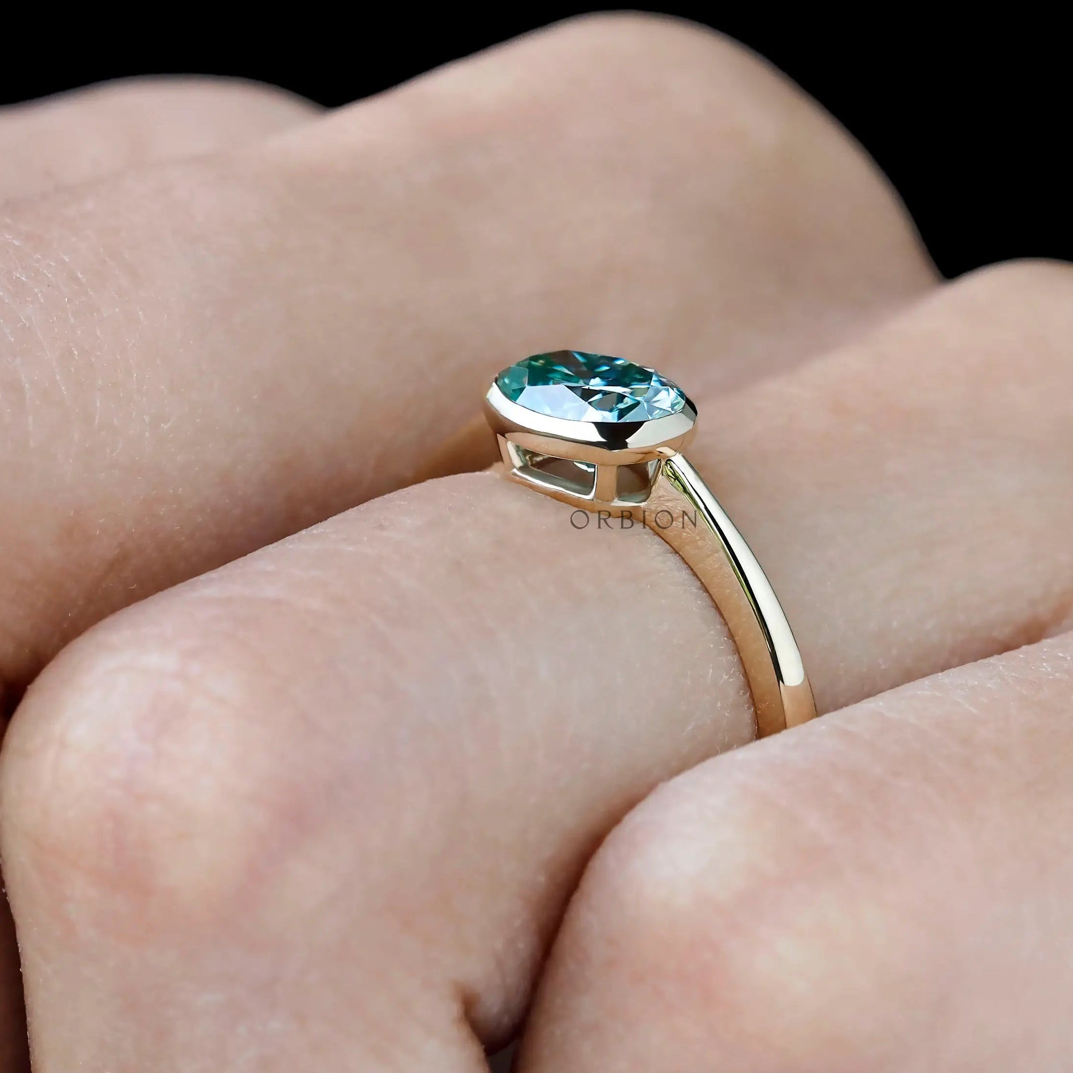 Minimal yellow gold engagement ring with blue green moissanite center stone