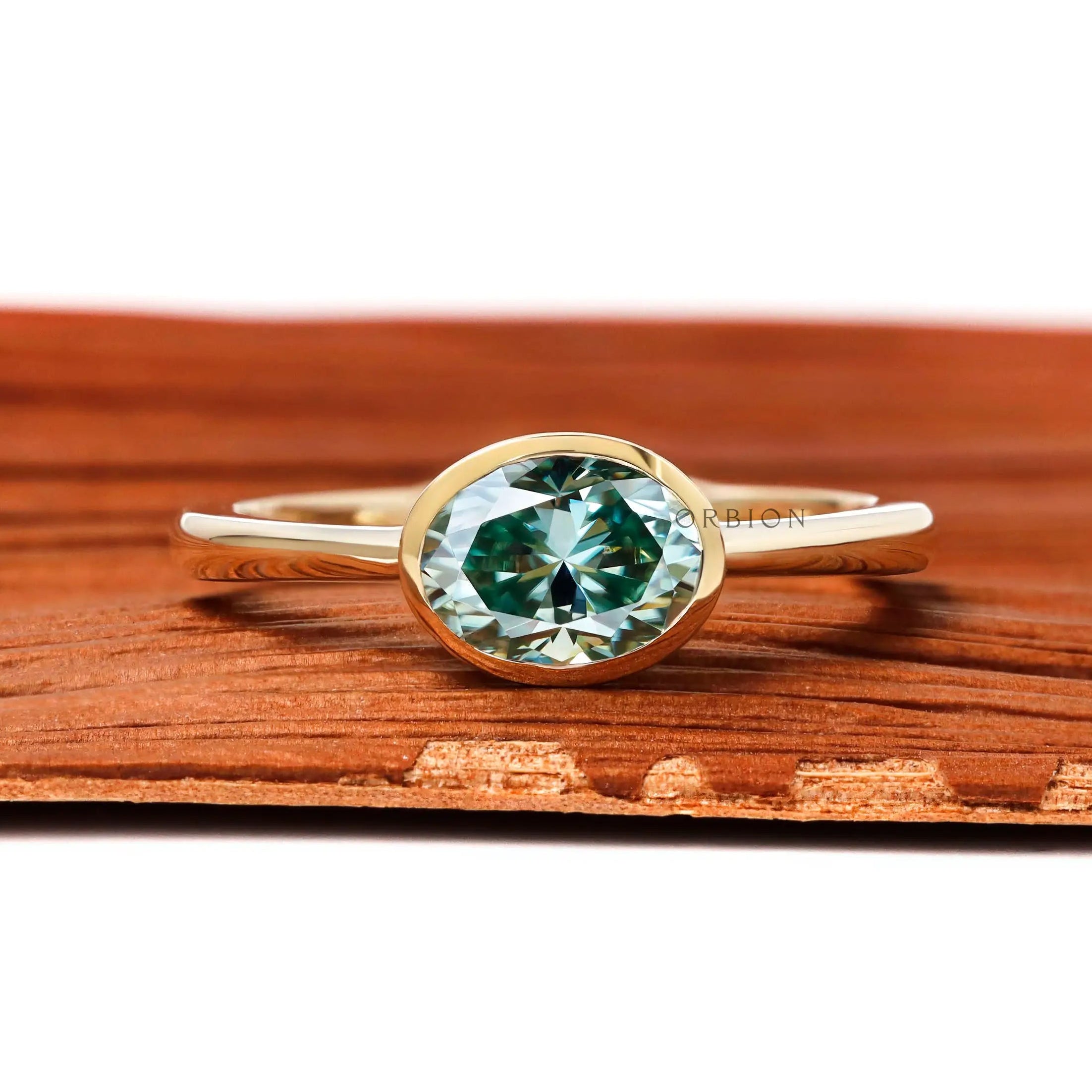Blue green oval moissanite east west bezel set engagement ring in 10k yellow gold