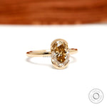 Centered closeup of oval champagne moissanite in floating bezel