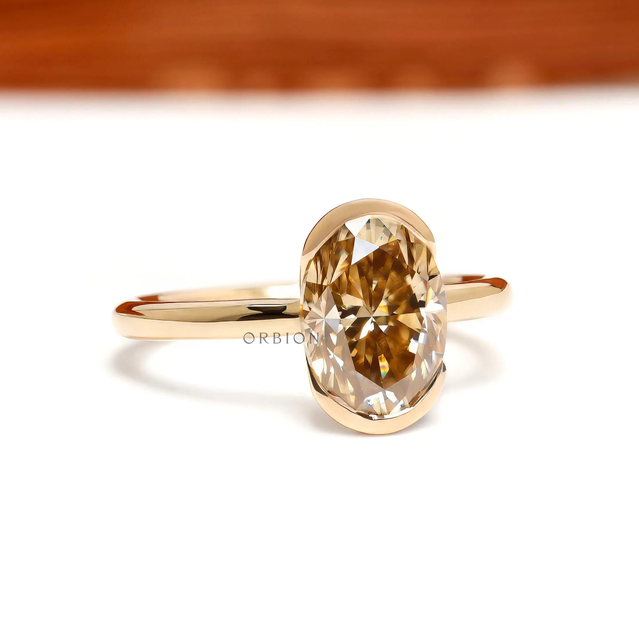 Centered closeup of oval champagne moissanite in floating bezel