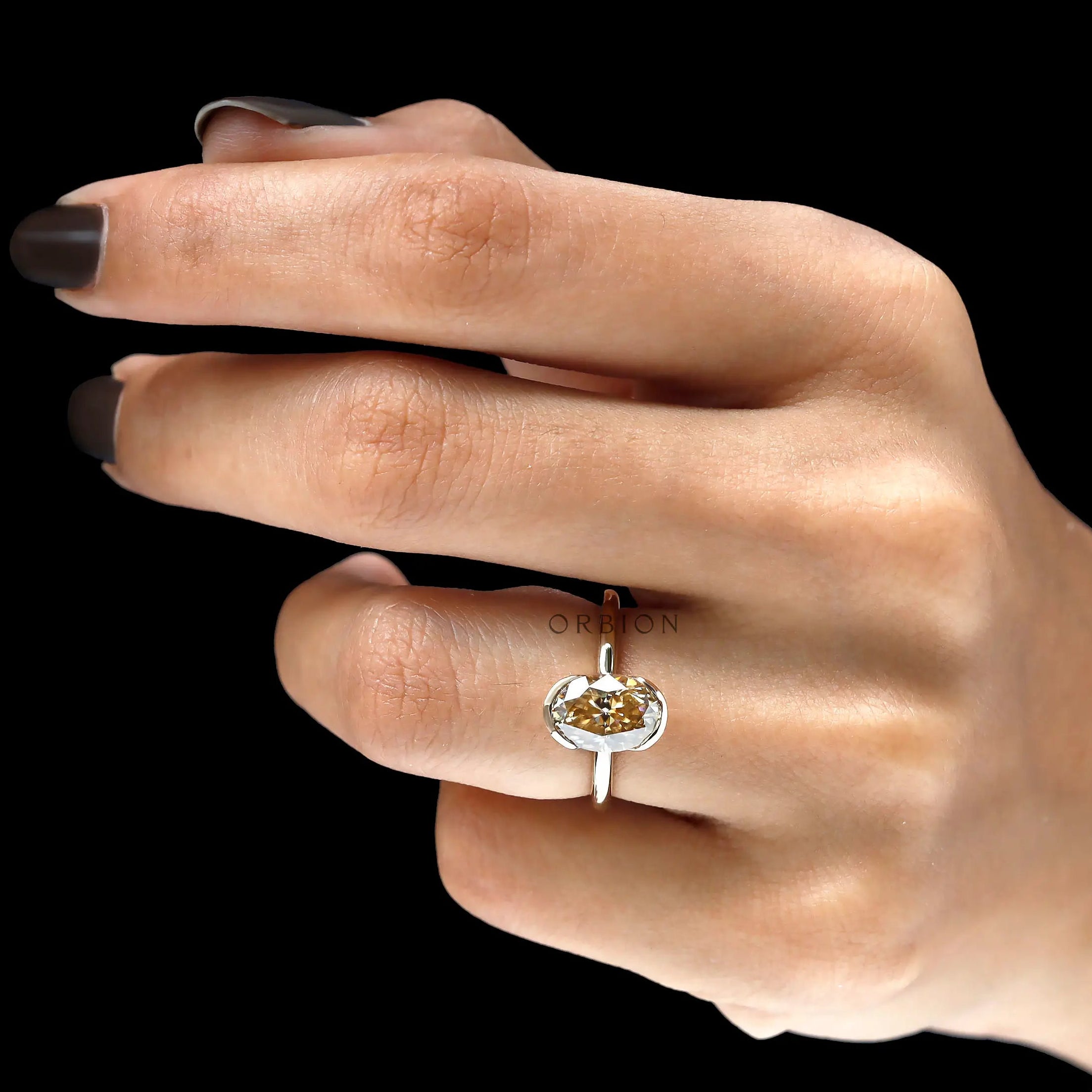 On hand top view of oval champagne moissanite engagement ring