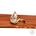 Angled view pear moissanite bypass solitaire ring in brushed matte gold