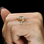 Side hand view pear moissanite bypass ring in brushed gold