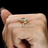 Side hand view pear moissanite bypass ring in brushed gold