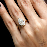 Close hand view pear moissanite bypass engagement ring in matte gold