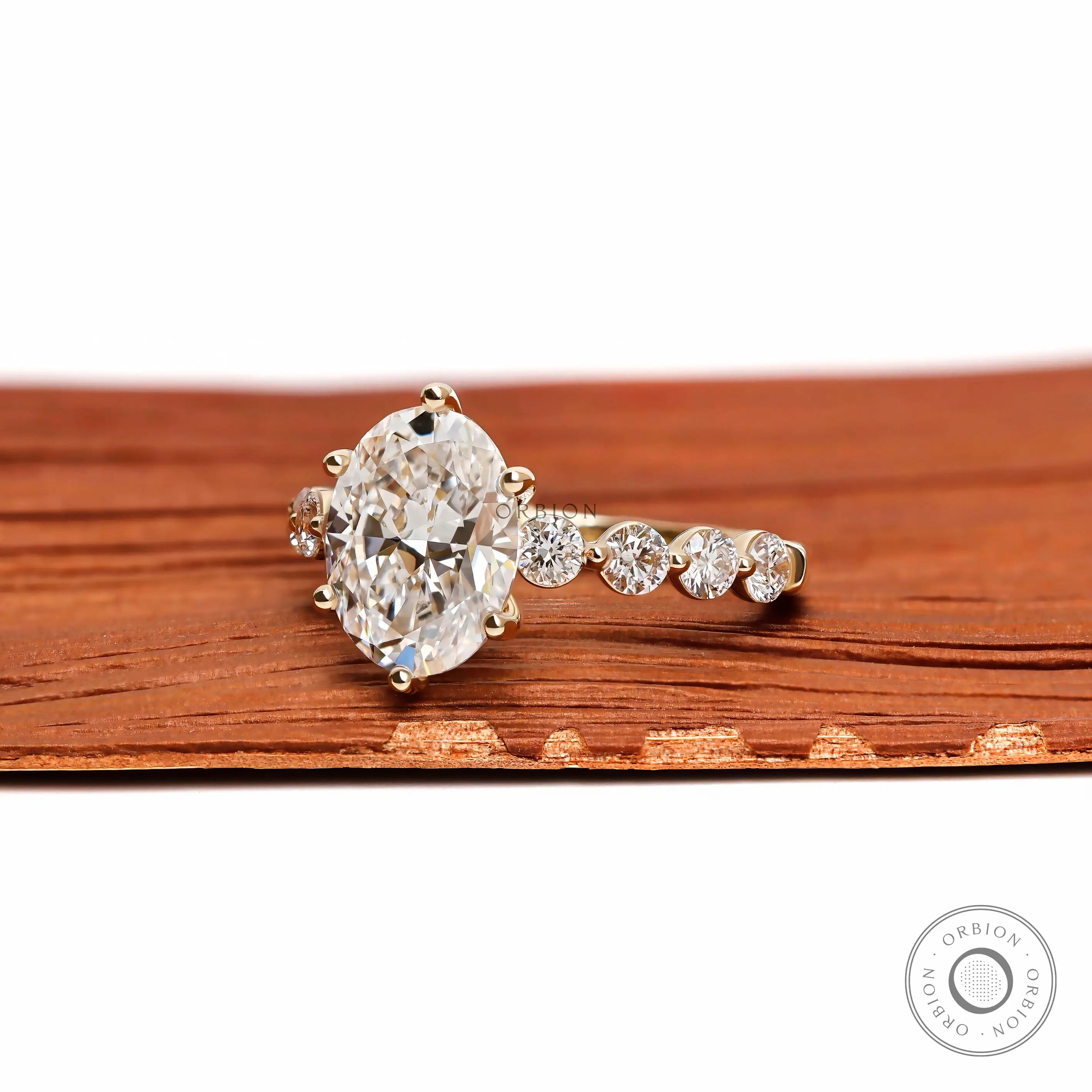 Angled view oval diamond ring with round side stones in gold