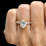 Oval diamond ring with round side stones shown on hand