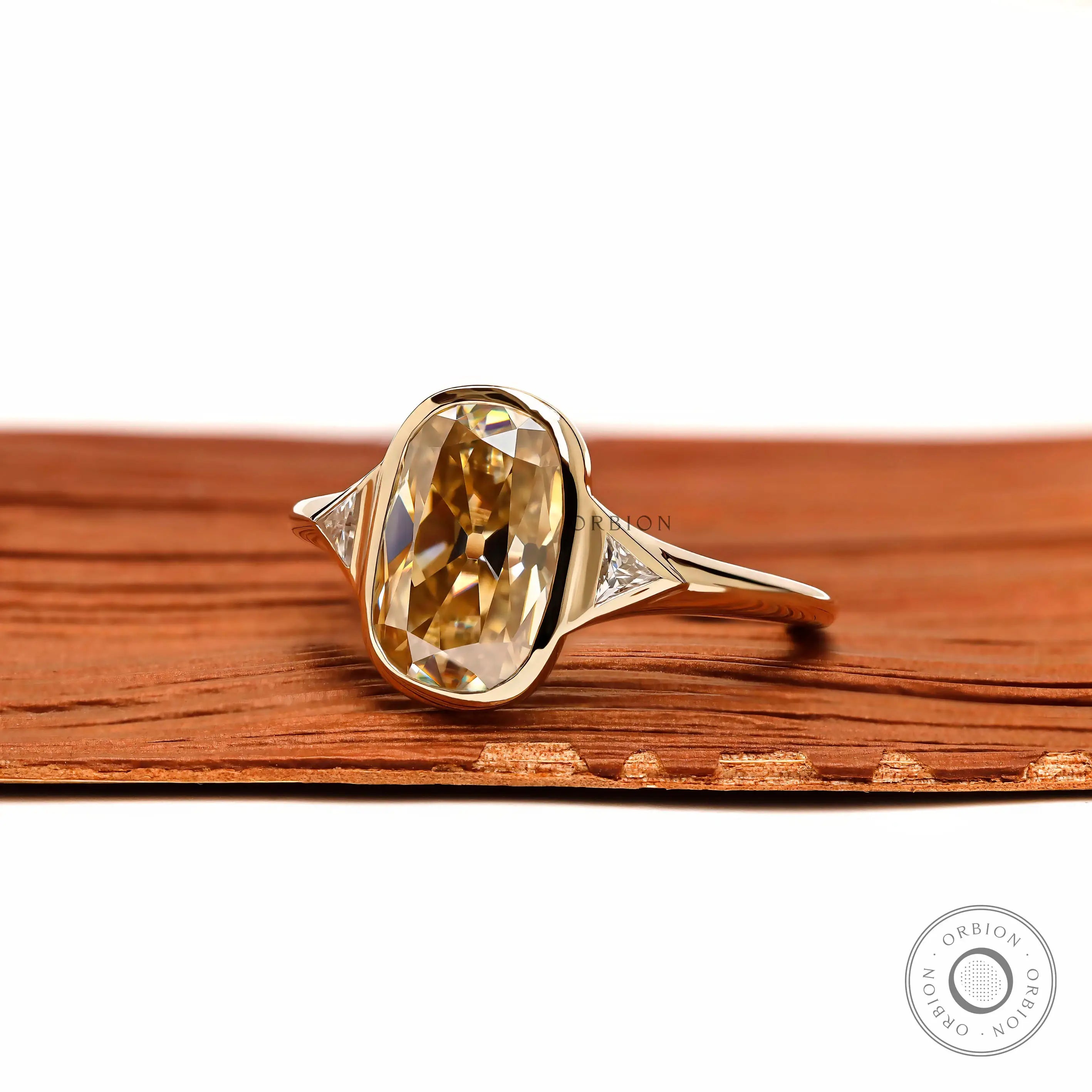 Angled front view champagne cushion moissanite three stone ring in yellow gold