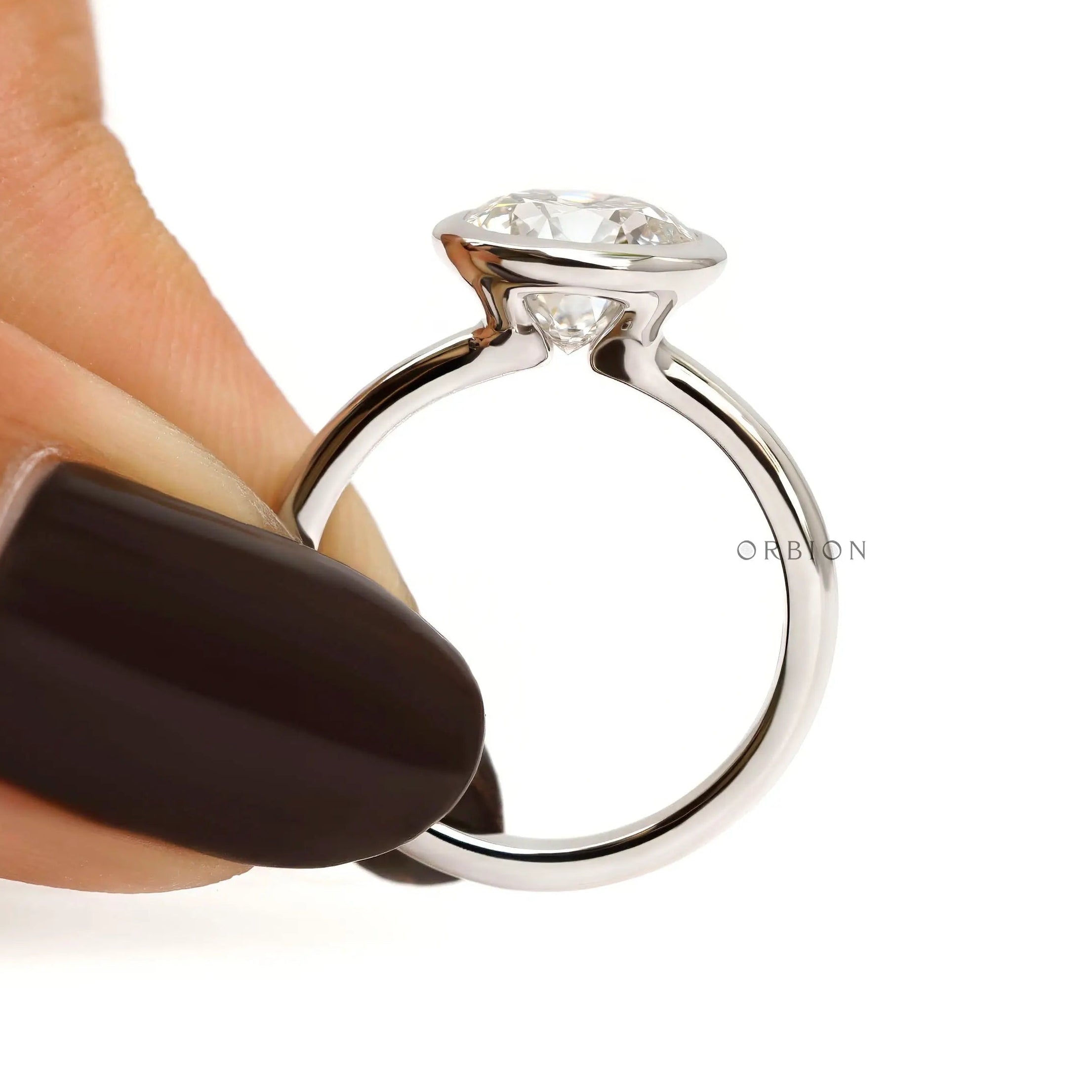 Finger held side view round bezel set diamond solitaire ring