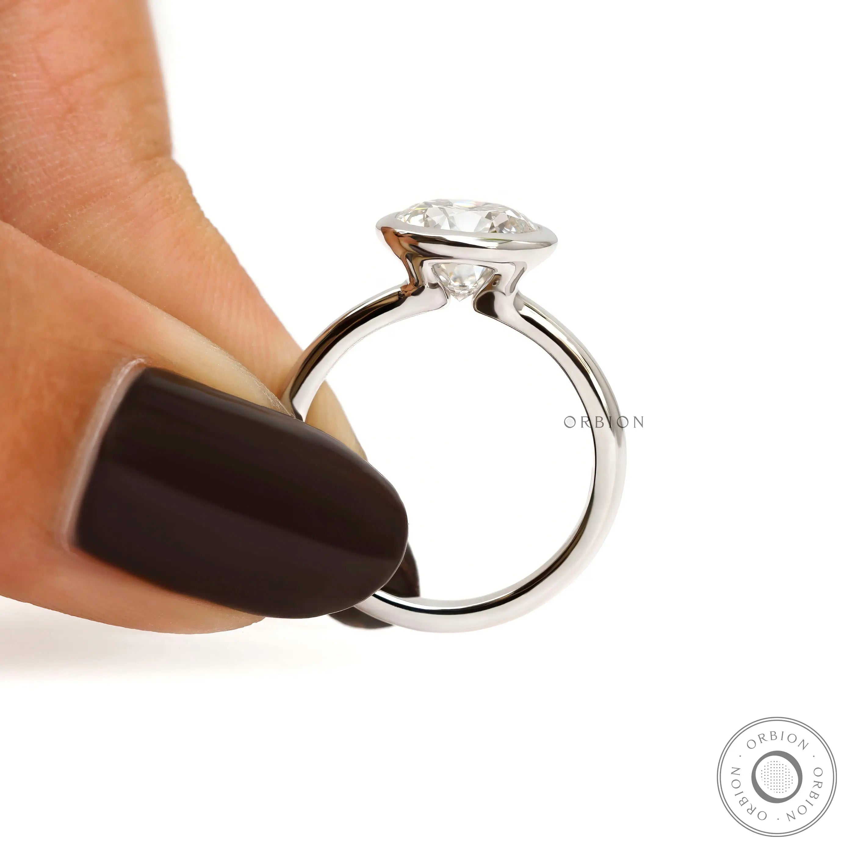 Finger held side view round bezel set diamond solitaire ring