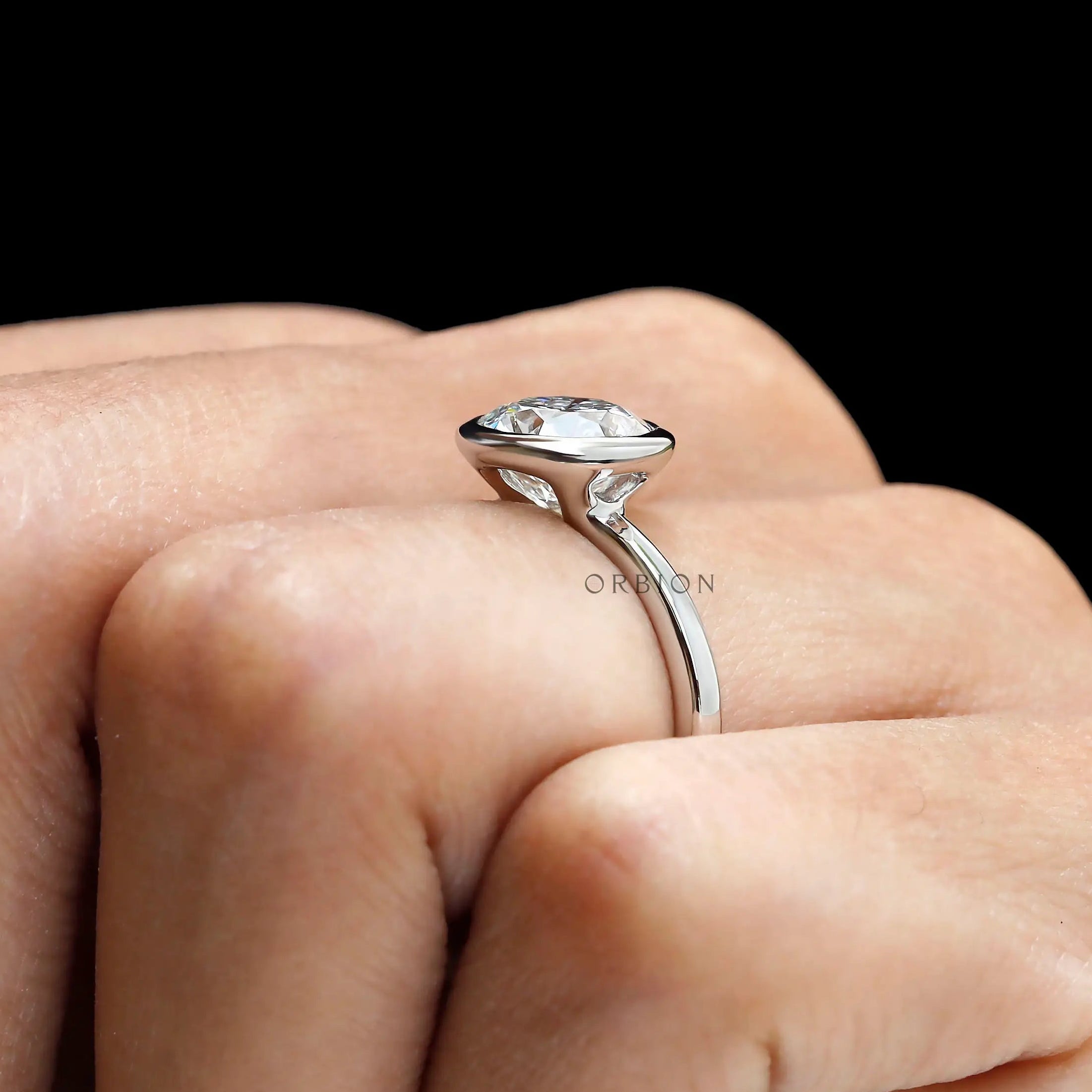 Side hand view elevated bezel set round diamond ring