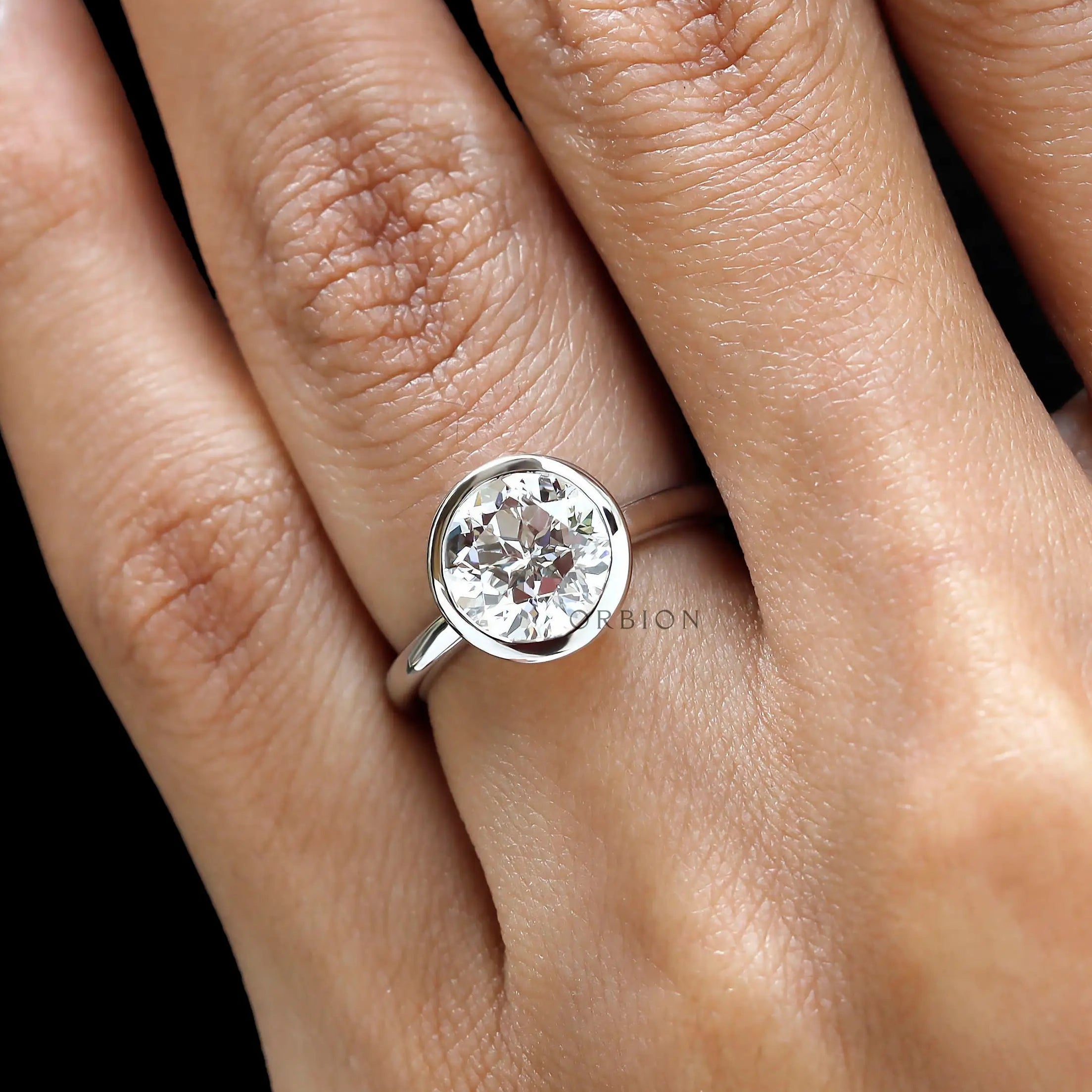 Close hand view round star cut bezel engagement ring