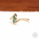 Angled front view of marquise green lab diamond bypass ring in yellow gold.