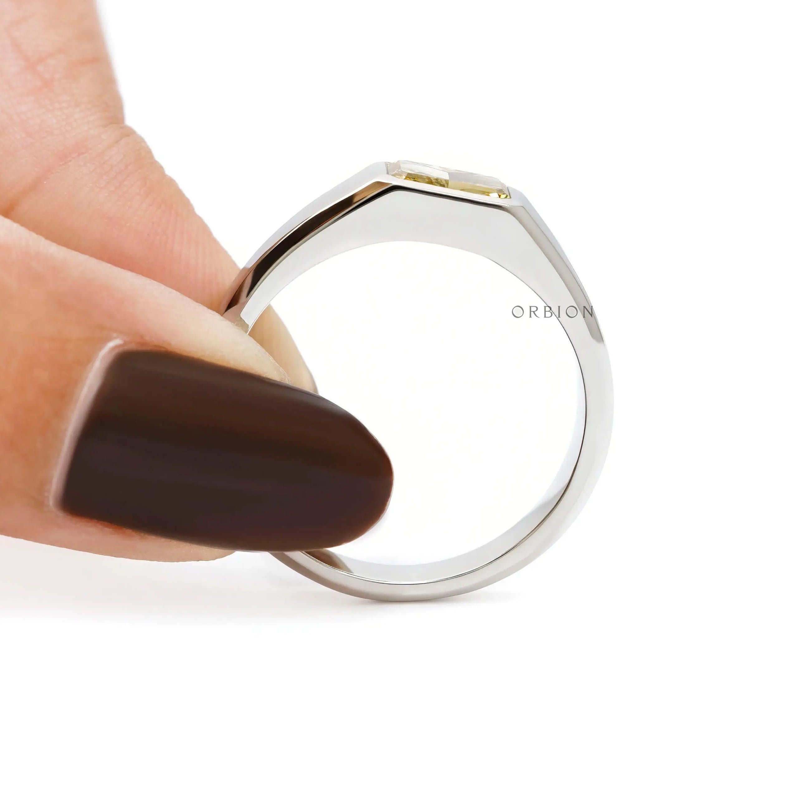Side view of platinum signet ring held between fingers.