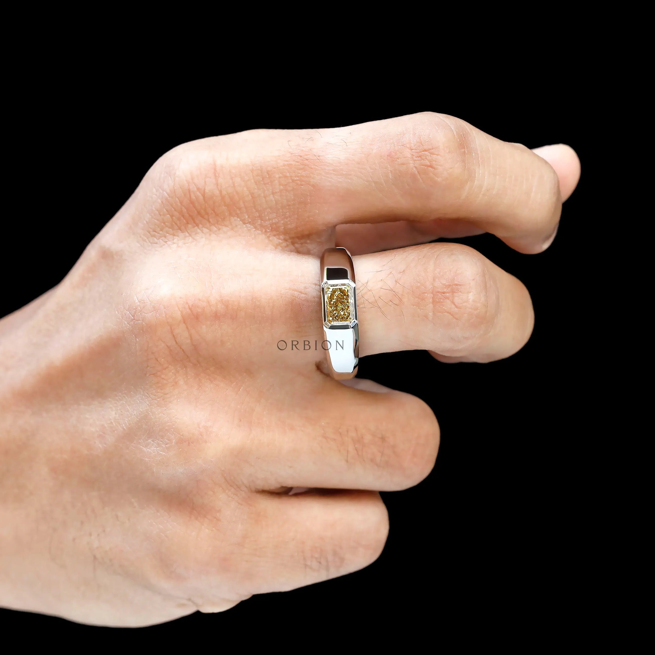 Hand shot displaying bold platinum signet ring with yellow diamond.