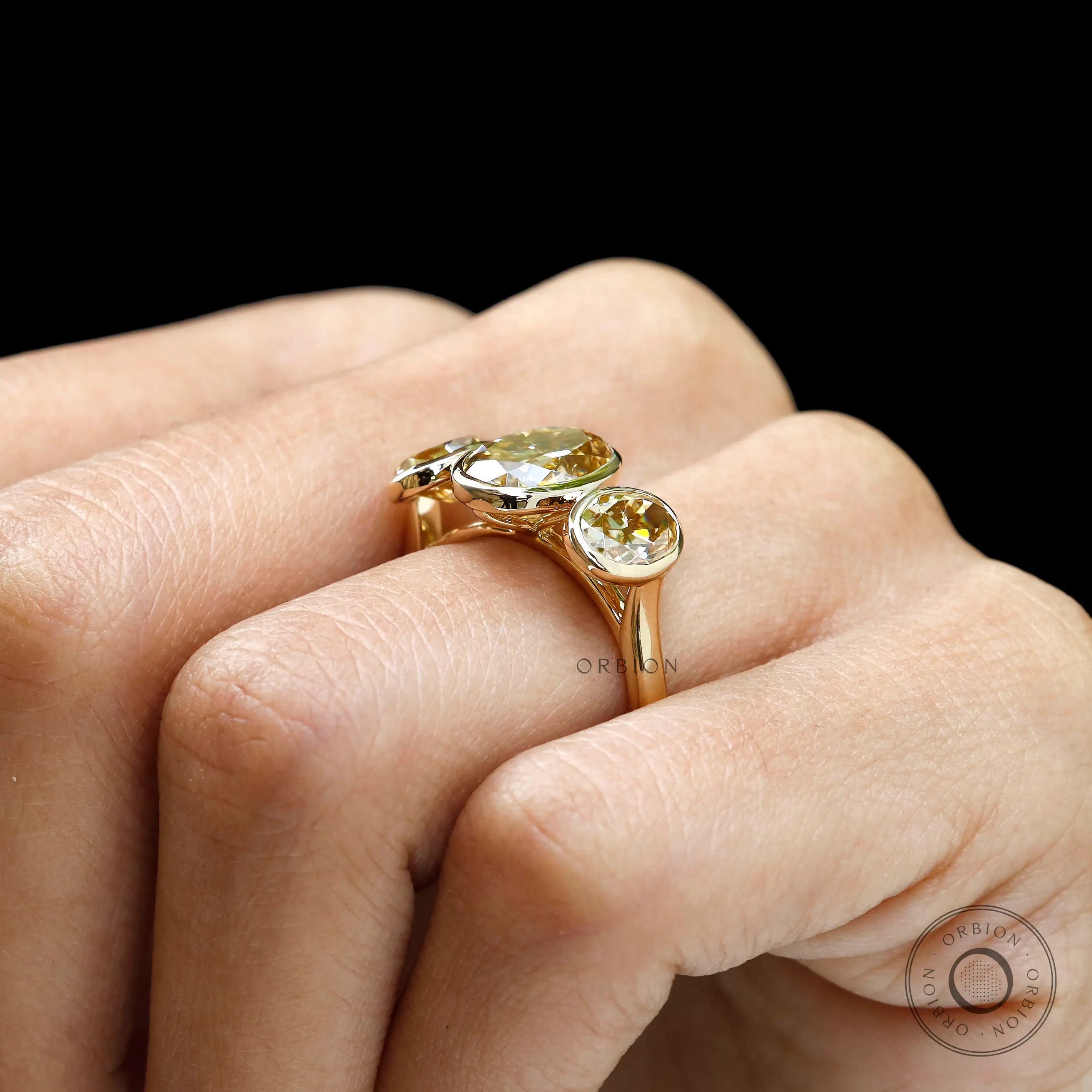 Worn side view of bezel set three stone oval ring.
