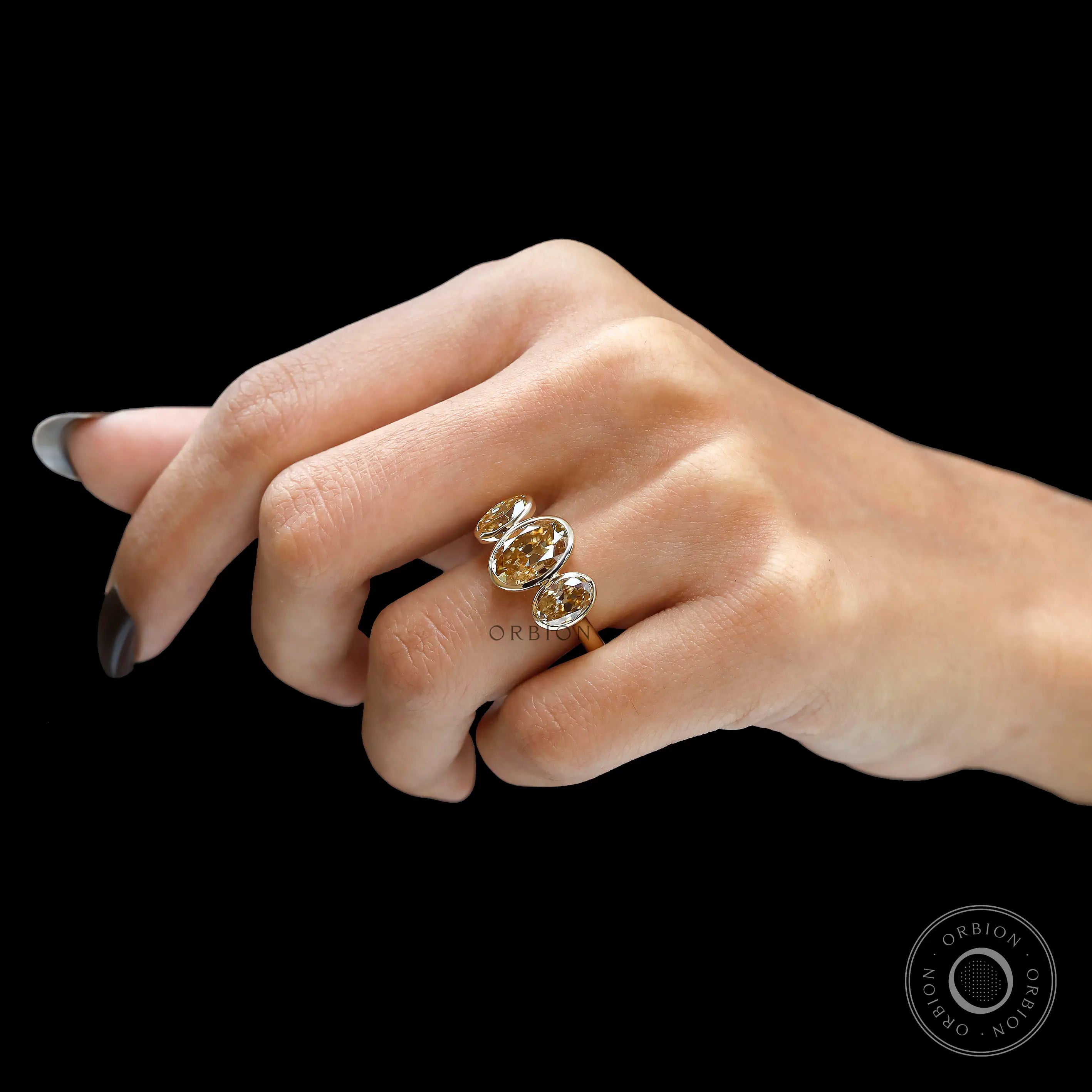 Hand view featuring light champagne three stone moissanite ring.