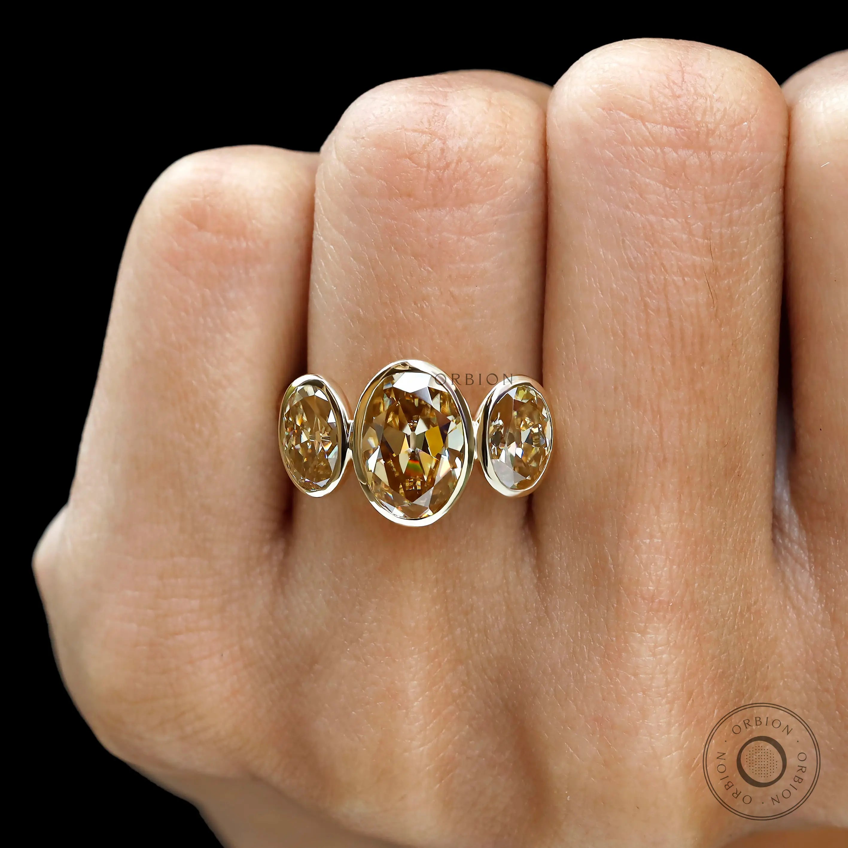 Front worn view of bezel set oval three stone ring.