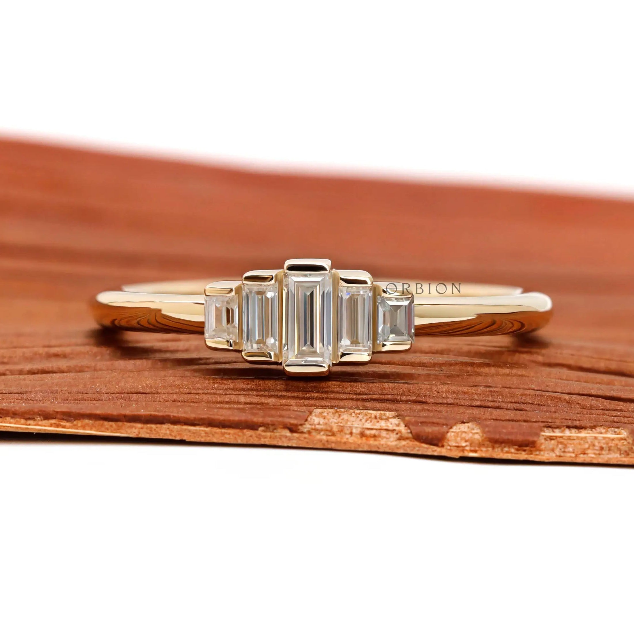 Front view of dainty five stone baguette moissanite ring in yellow gold.
