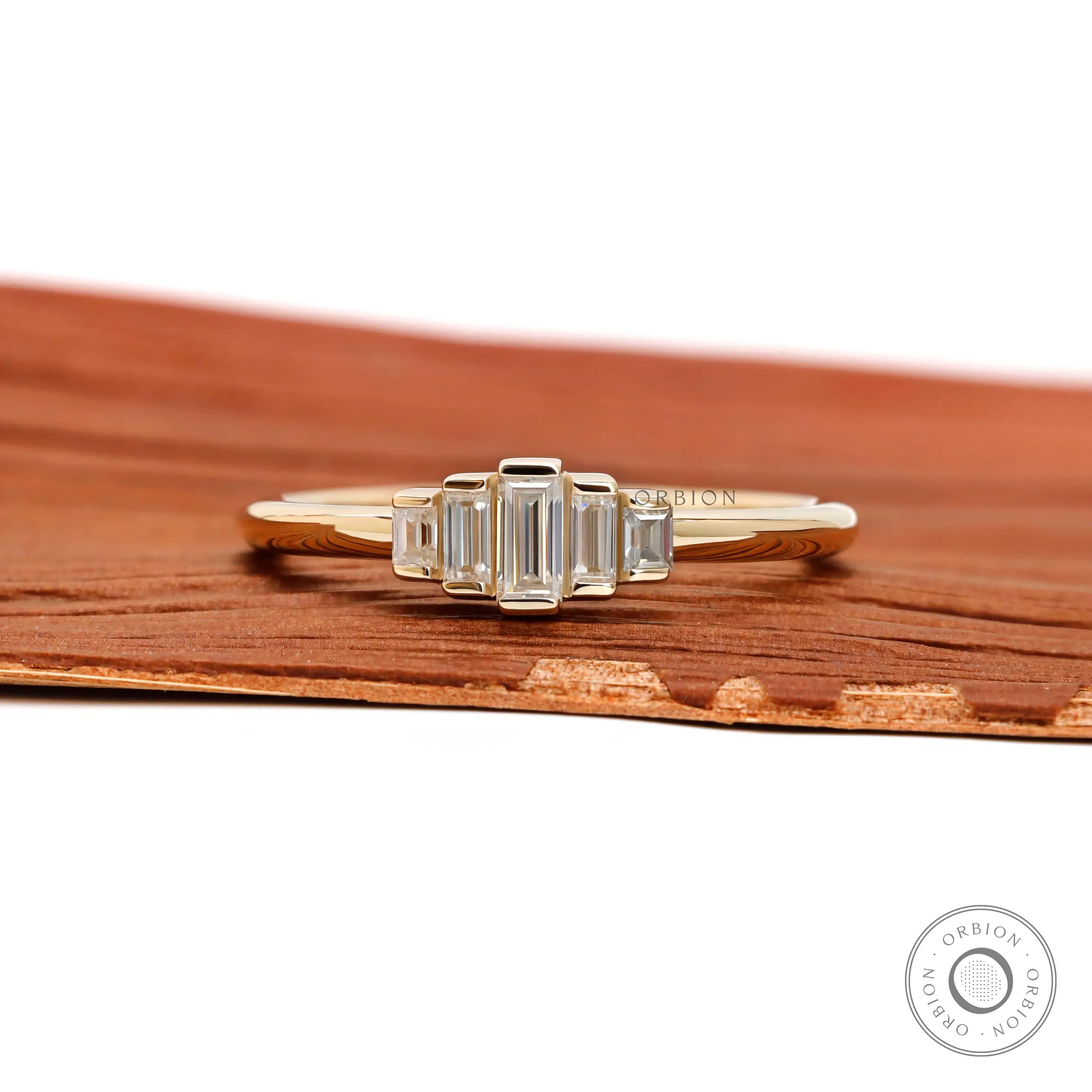 Front view of dainty five stone baguette moissanite ring in yellow gold.