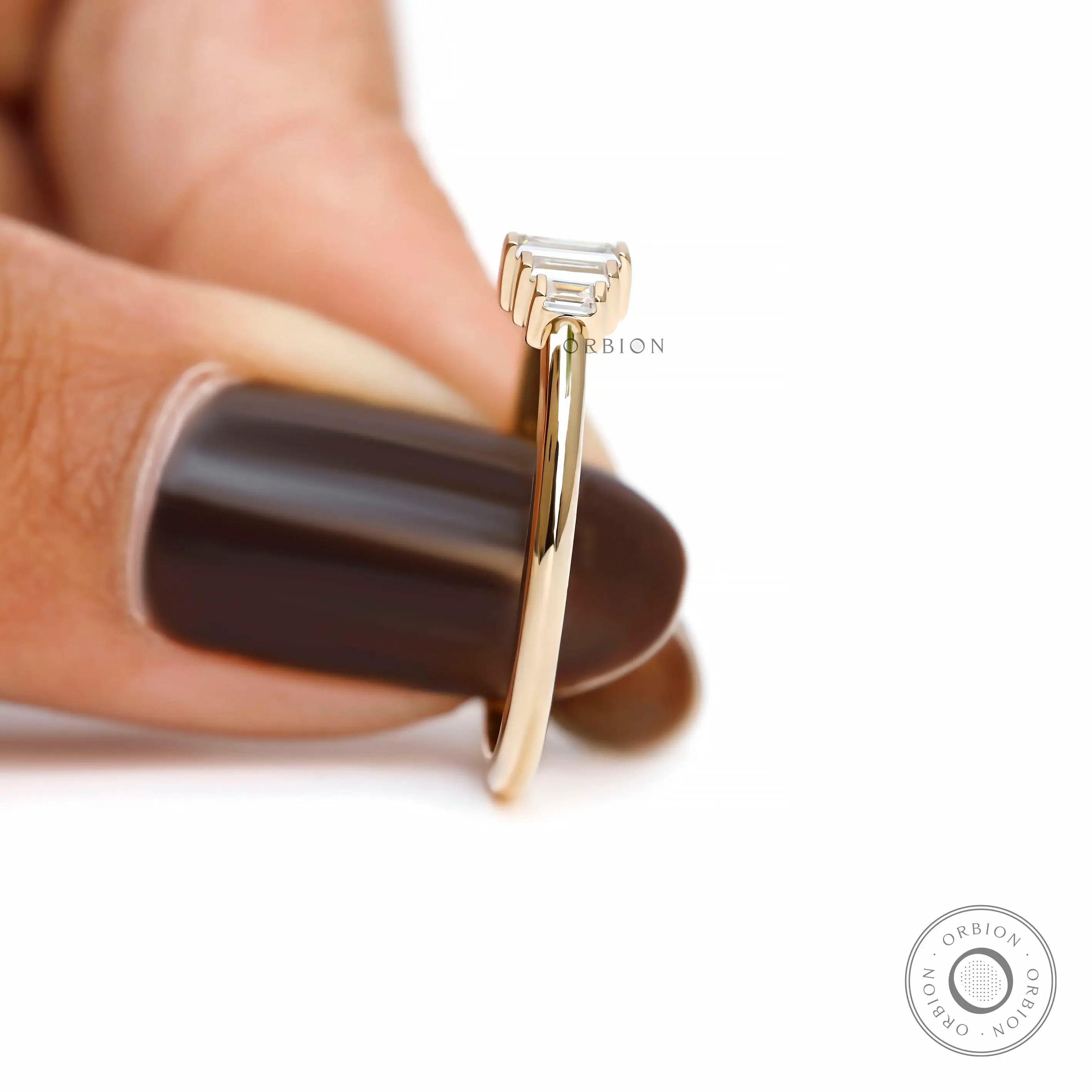 Side held view showing delicate ring profile and raised baguette setting.
