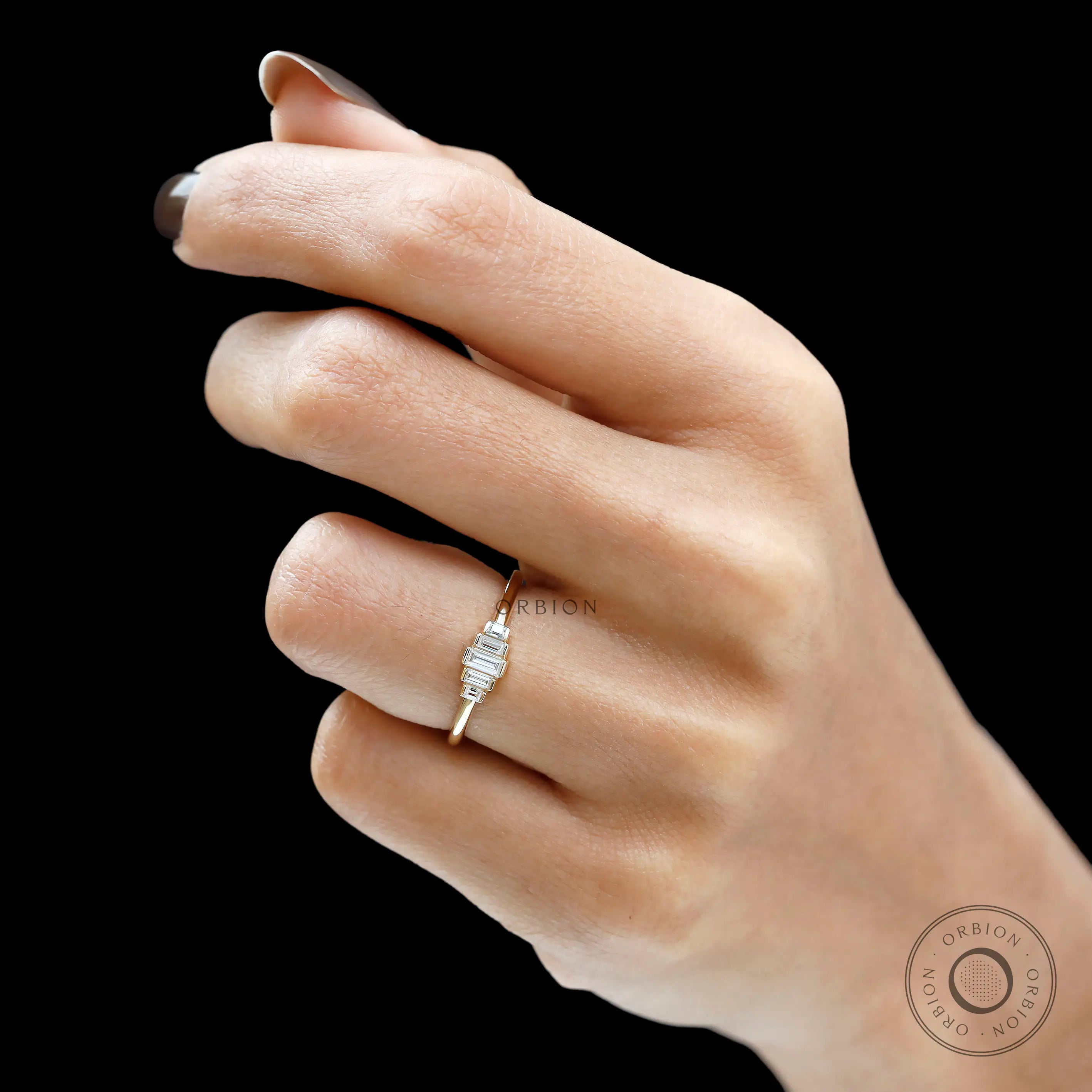 Hand view featuring dainty baguette moissanite ring in yellow gold.