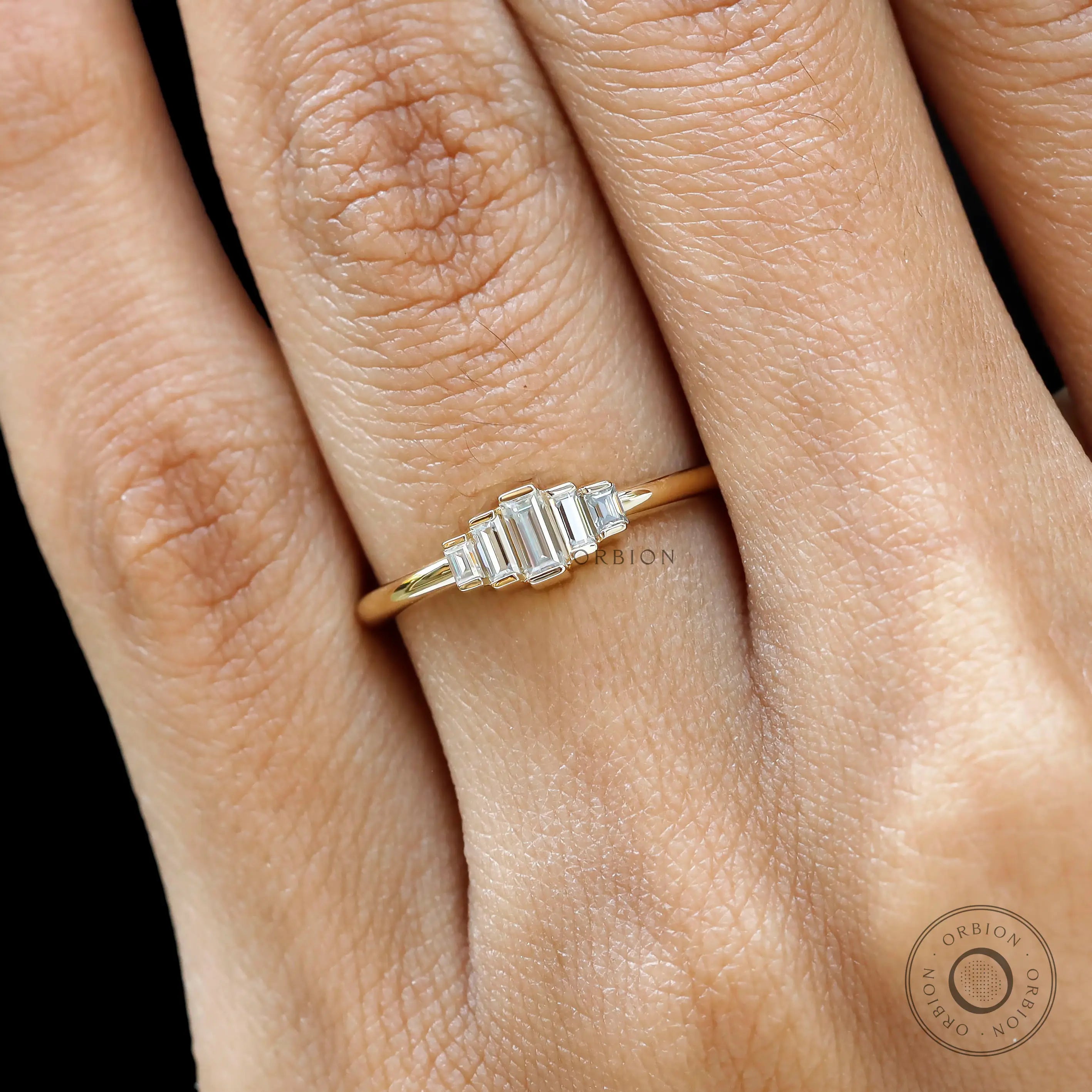 Close up worn view of tapered five stone baguette moissanite ring.