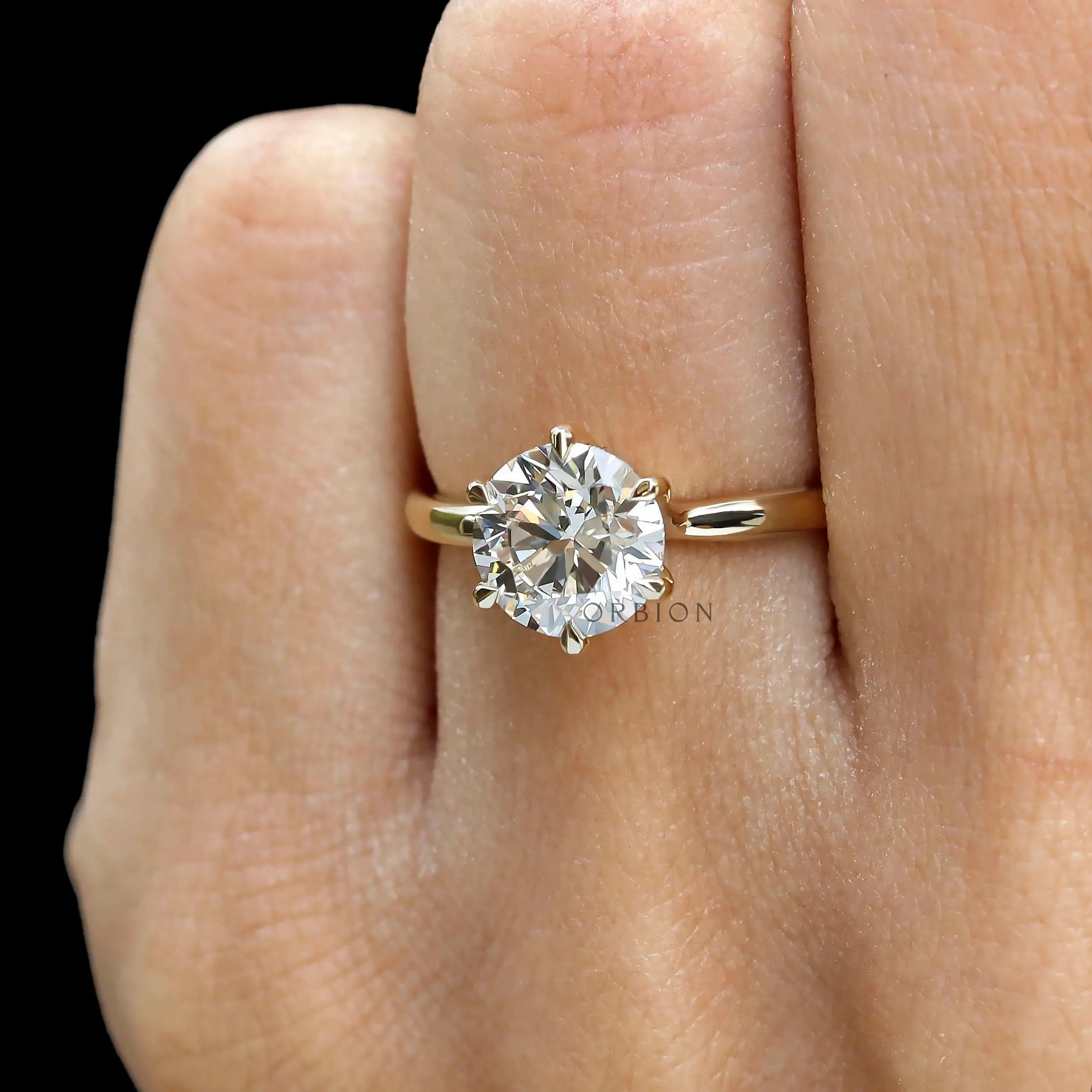 Front close view of round solitaire diamond ring on finger.