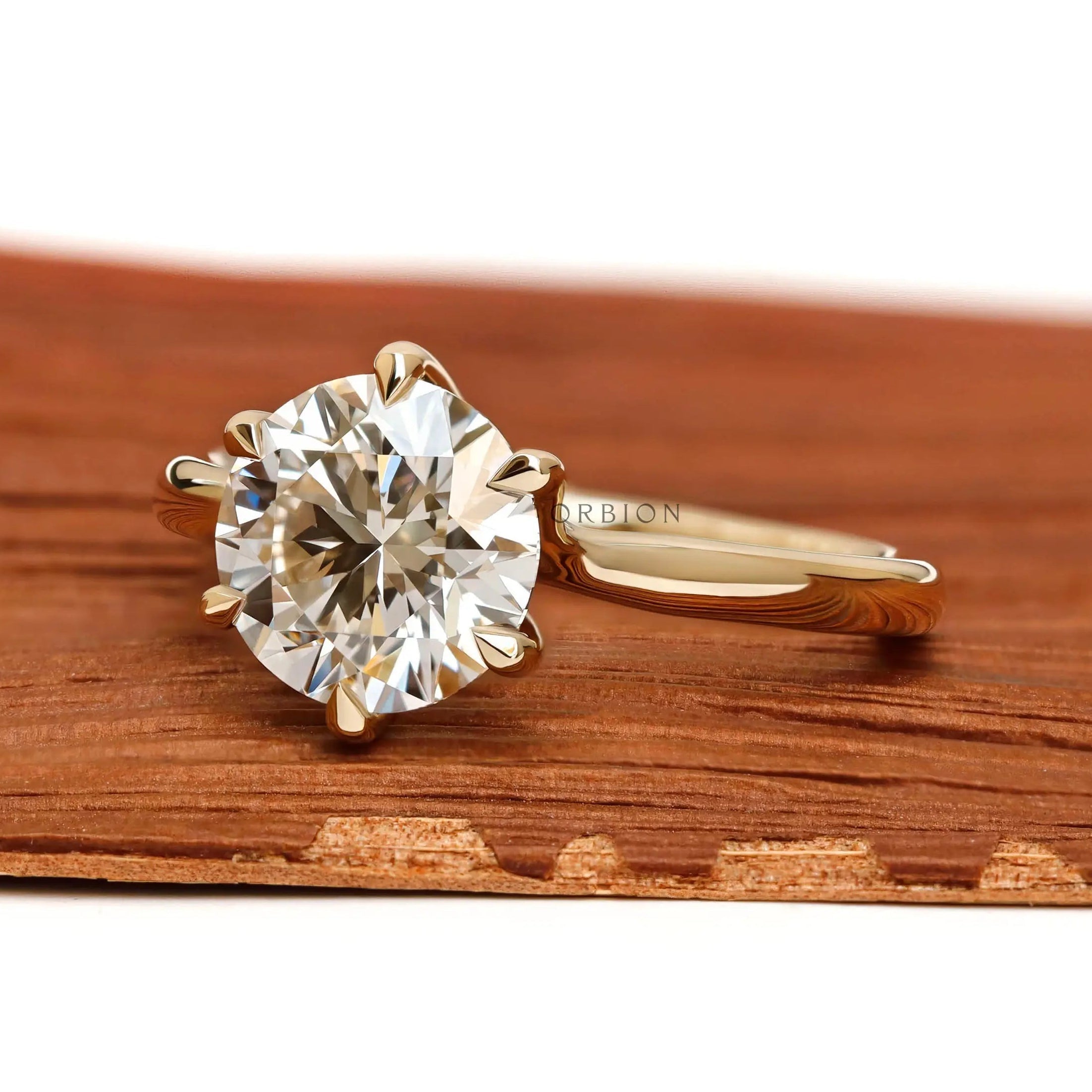Angled front view of round diamond solitaire yellow gold ring.