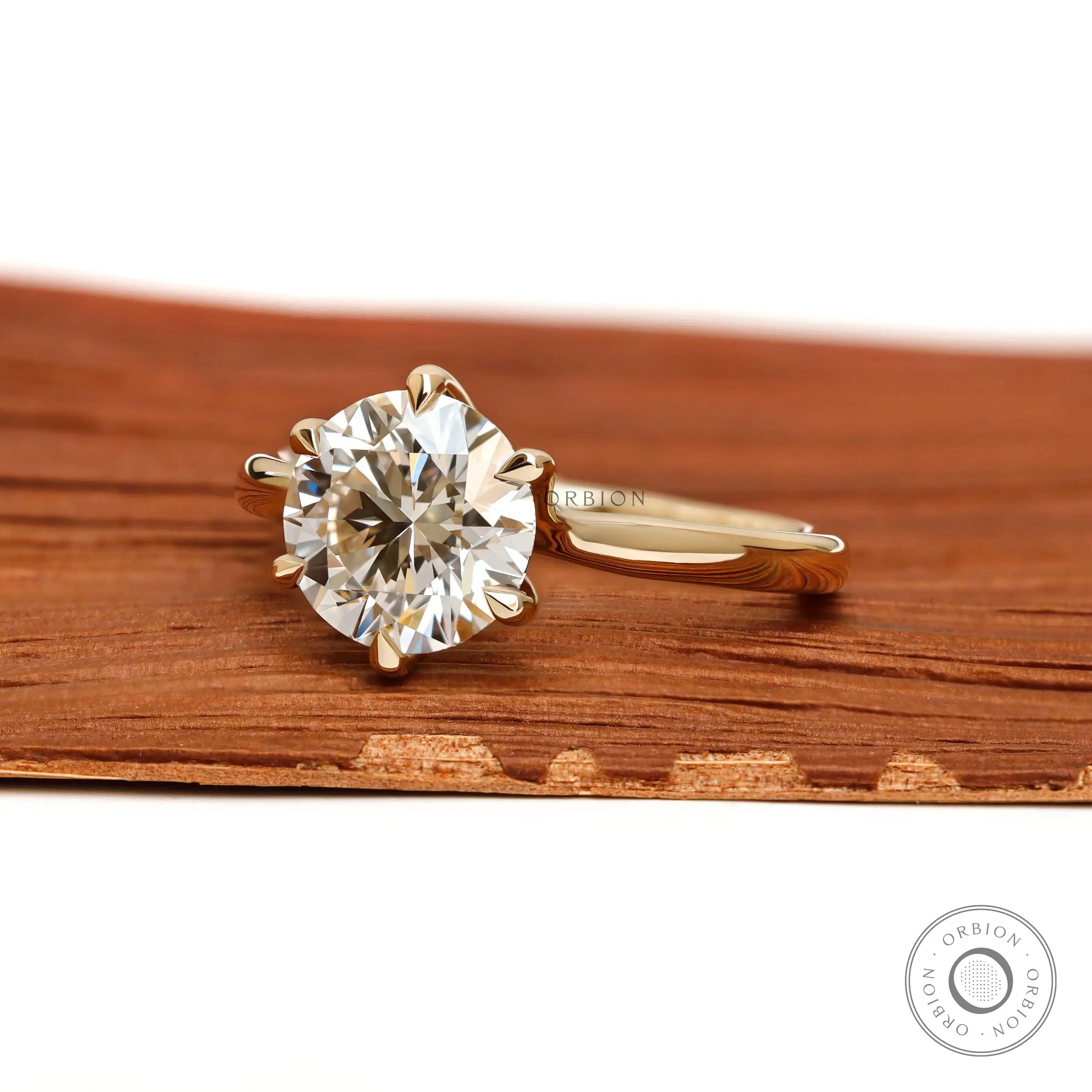 Angled front view of round diamond solitaire yellow gold ring.