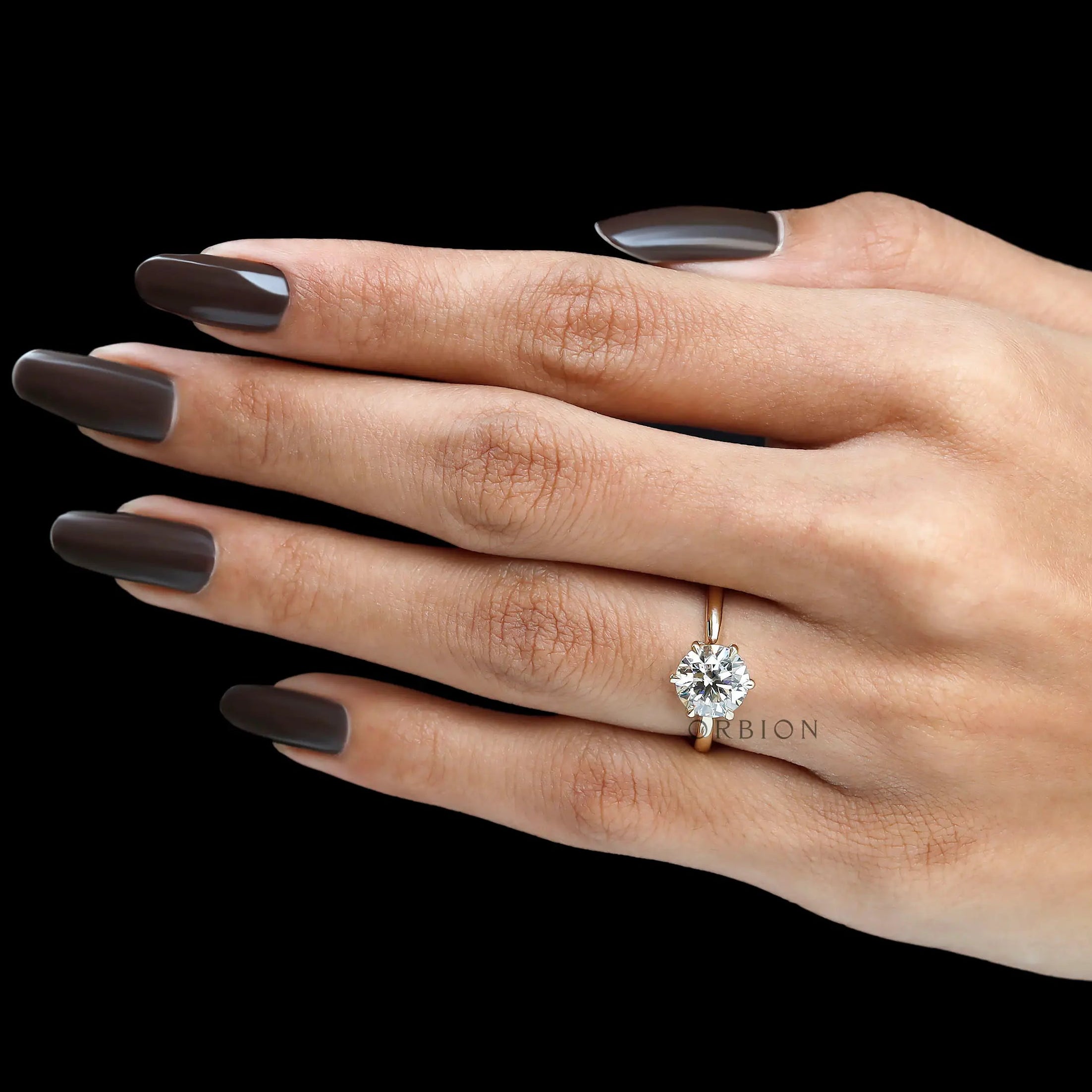 Hand view of round solitaire lab diamond ring in gold.