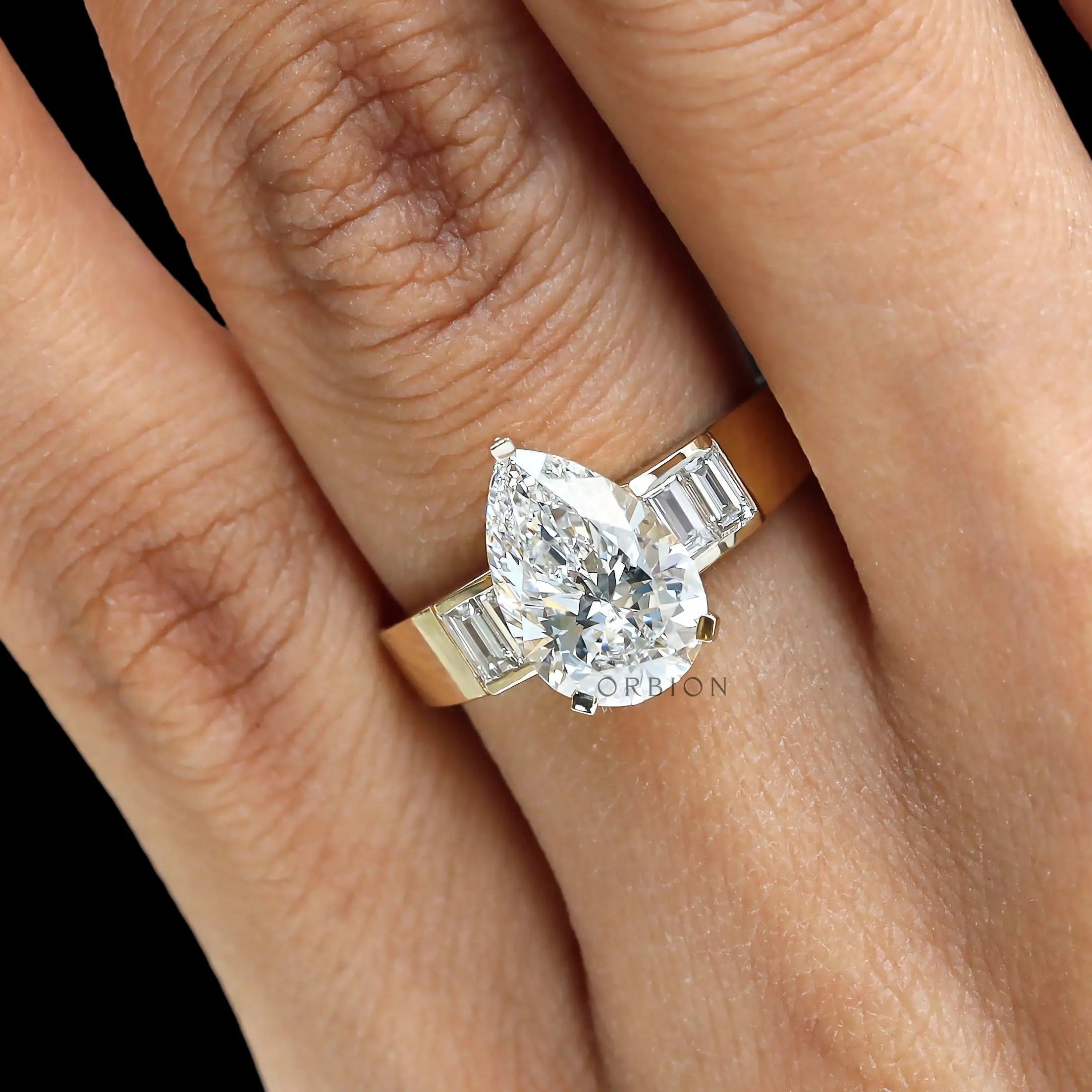 Close finger shot pear diamond ring in yellow gold