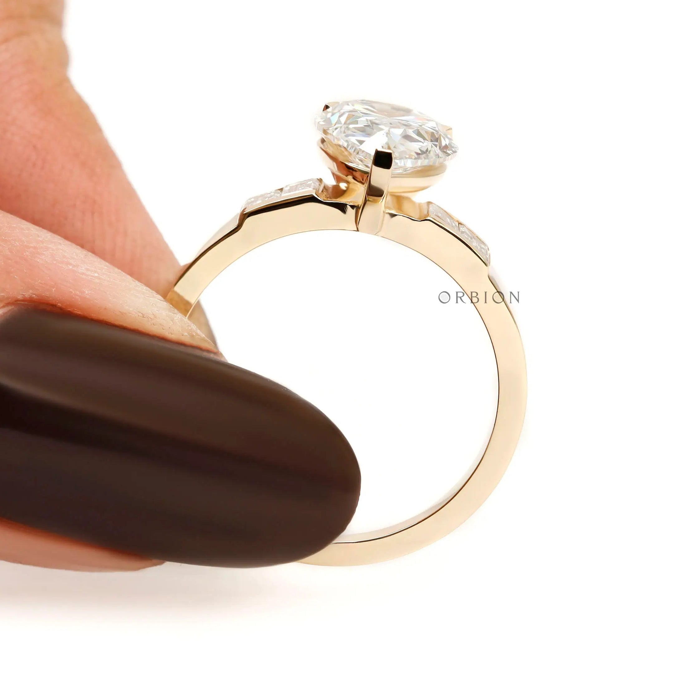 Finger held side view pear diamond ring with baguette shoulders