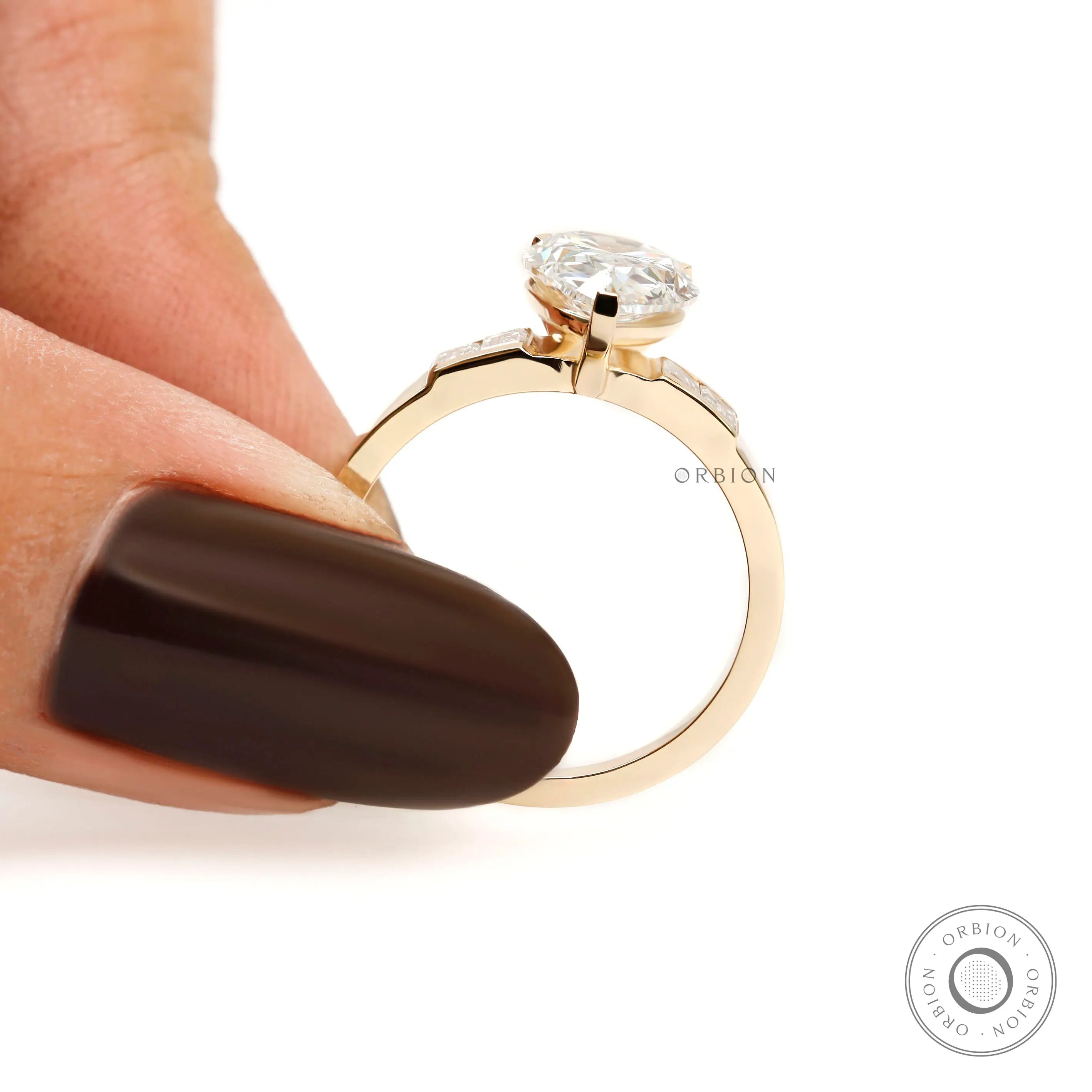 Finger held side view pear diamond ring with baguette shoulders