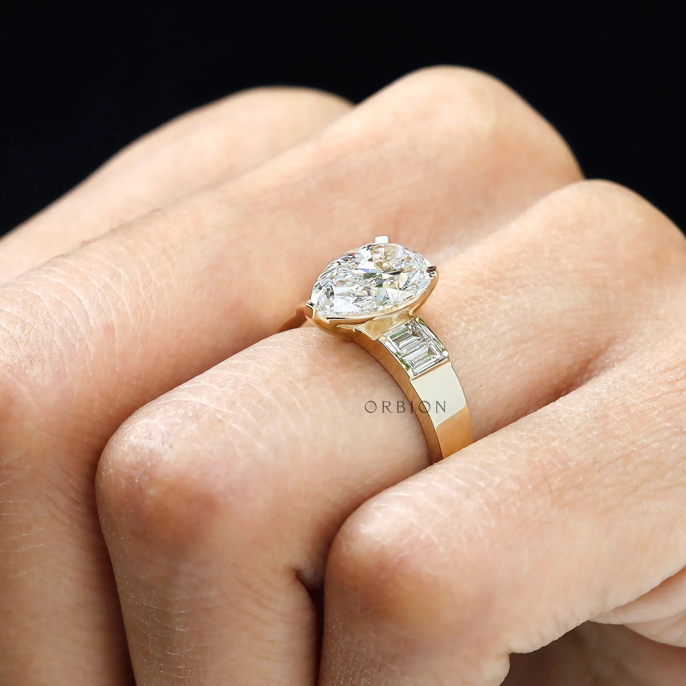 Close hand view pear lab diamond ring with baguette accents