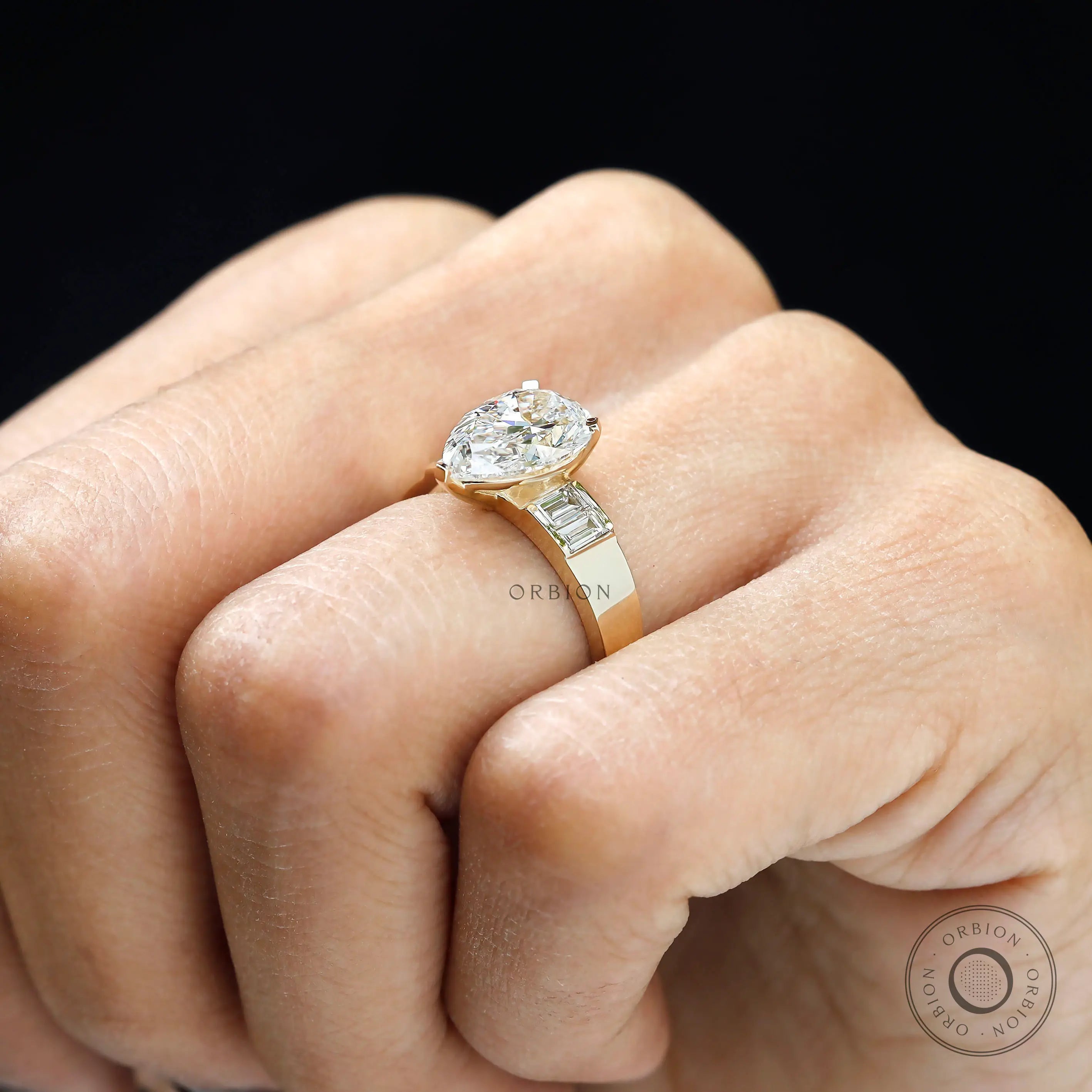 Close hand view pear lab diamond ring with baguette accents