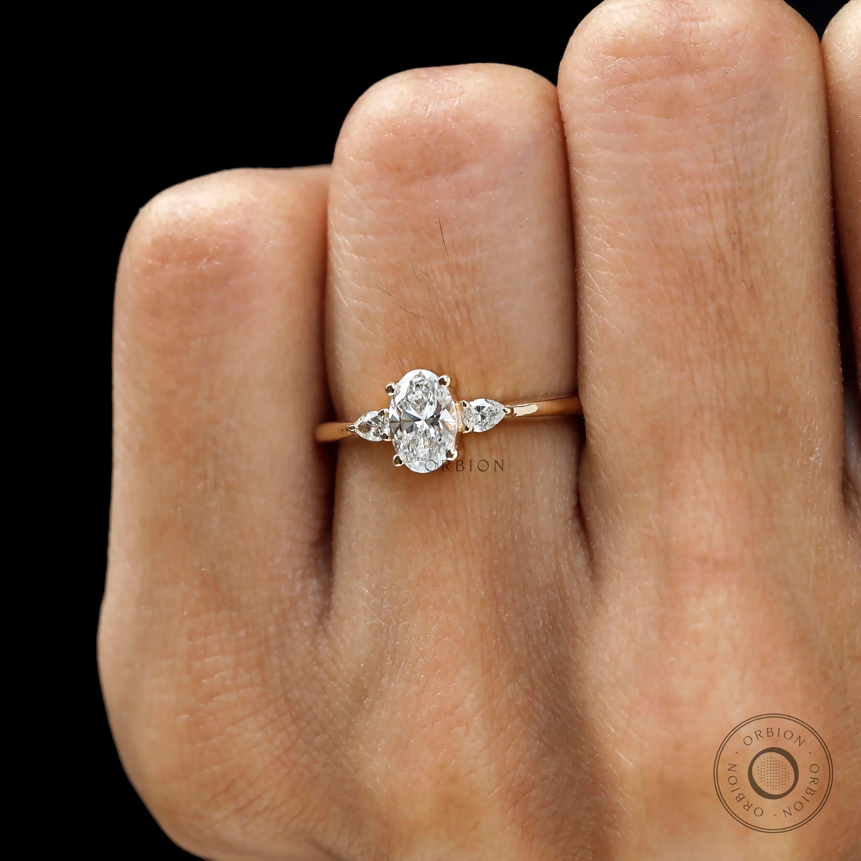 Close up of three stone oval and pear lab diamond wedding ring