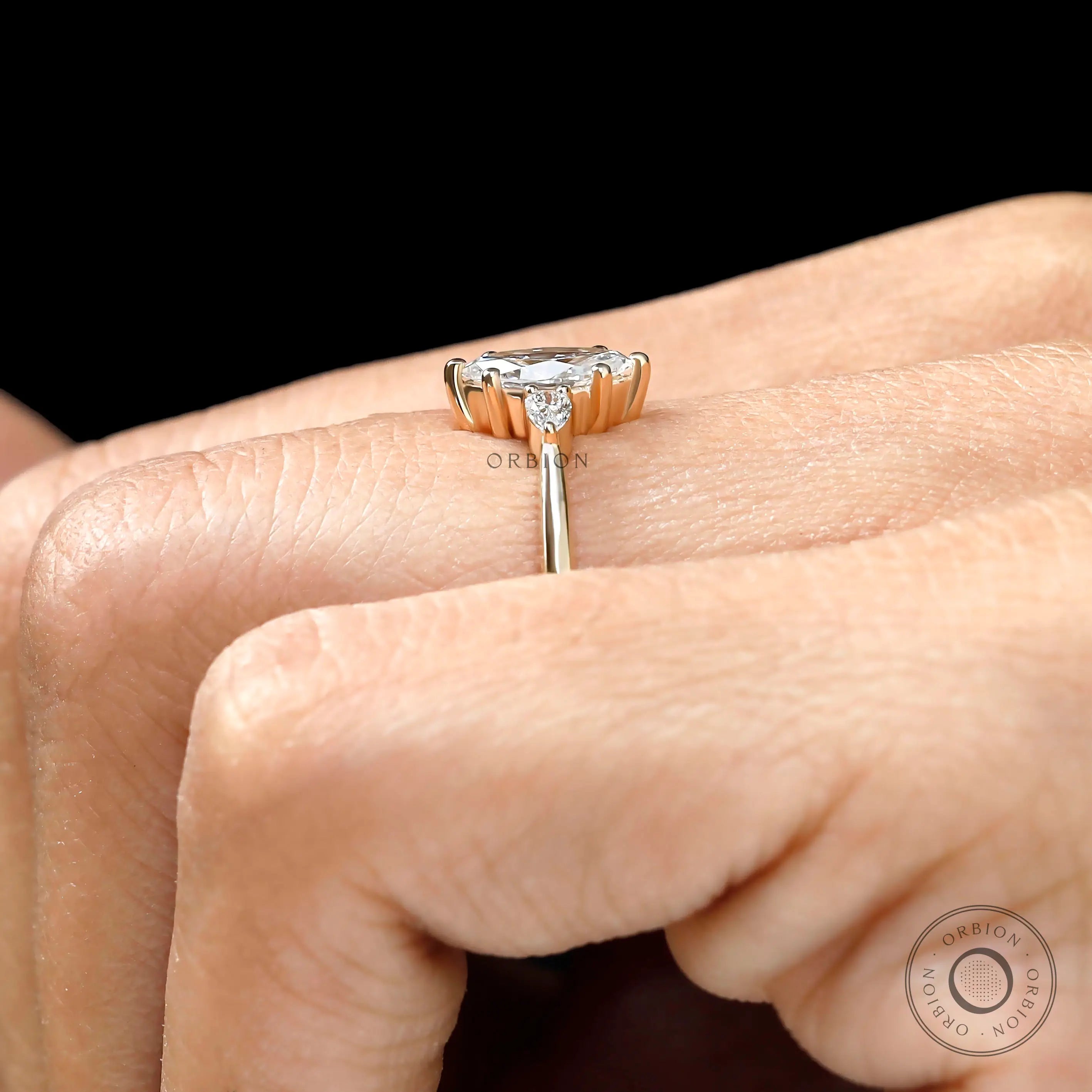 Marquise and pear three stone moissanite ring yellow gold on finger