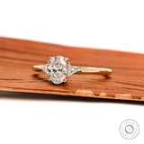 Side profile of oval three stone gold engagement ring