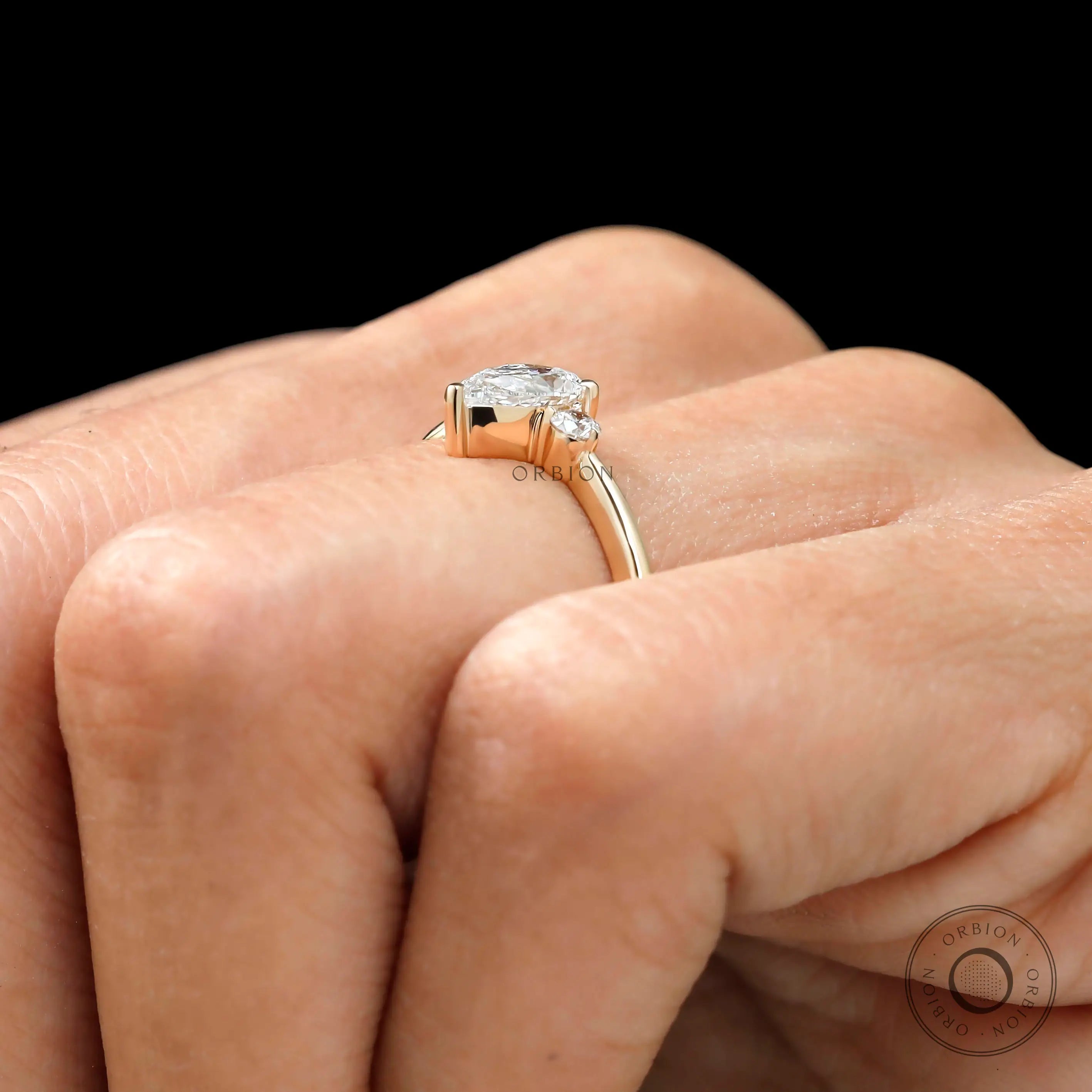 Pear cut center stone three stone ring side view