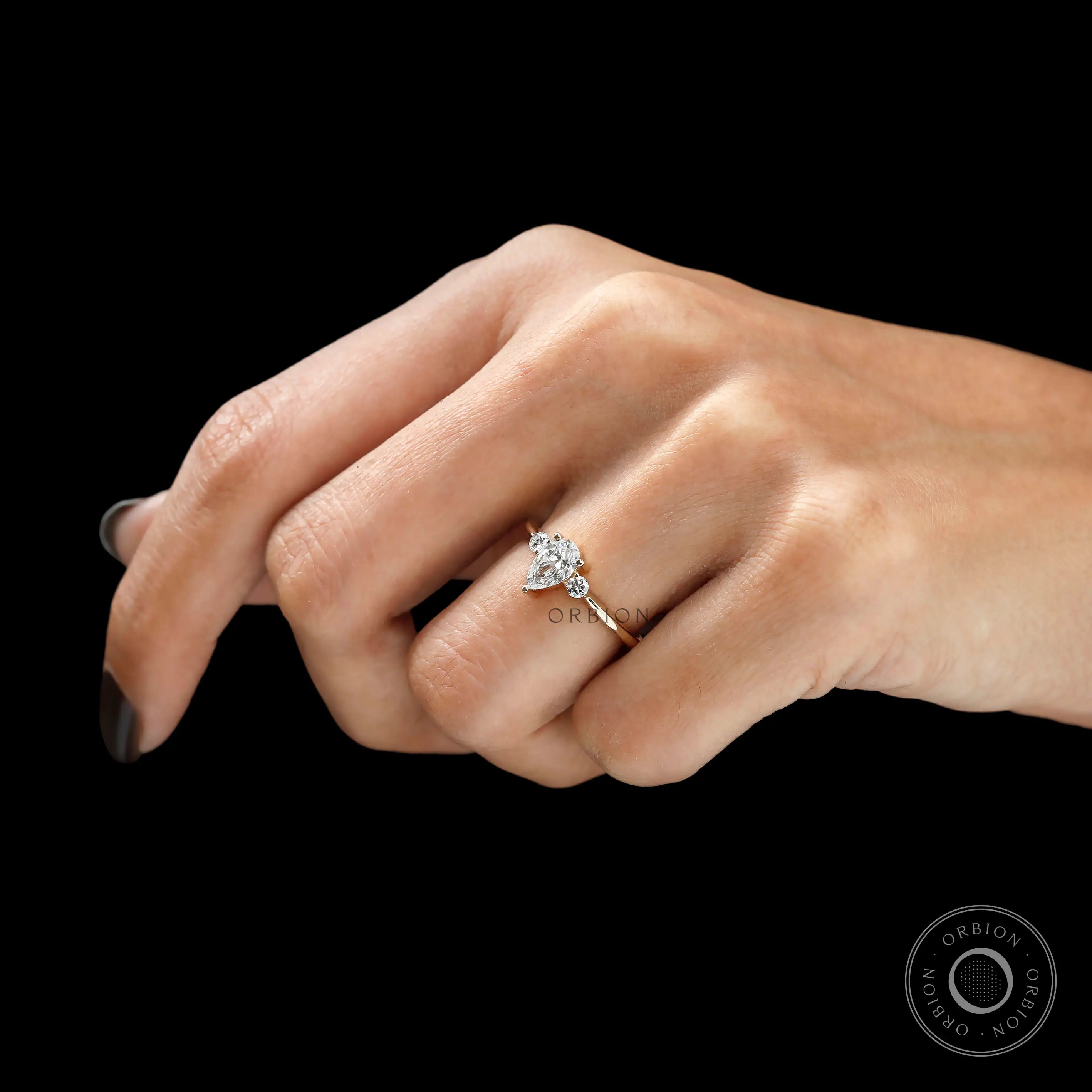 Minimal three stone engagement ring in yellow gold on finger